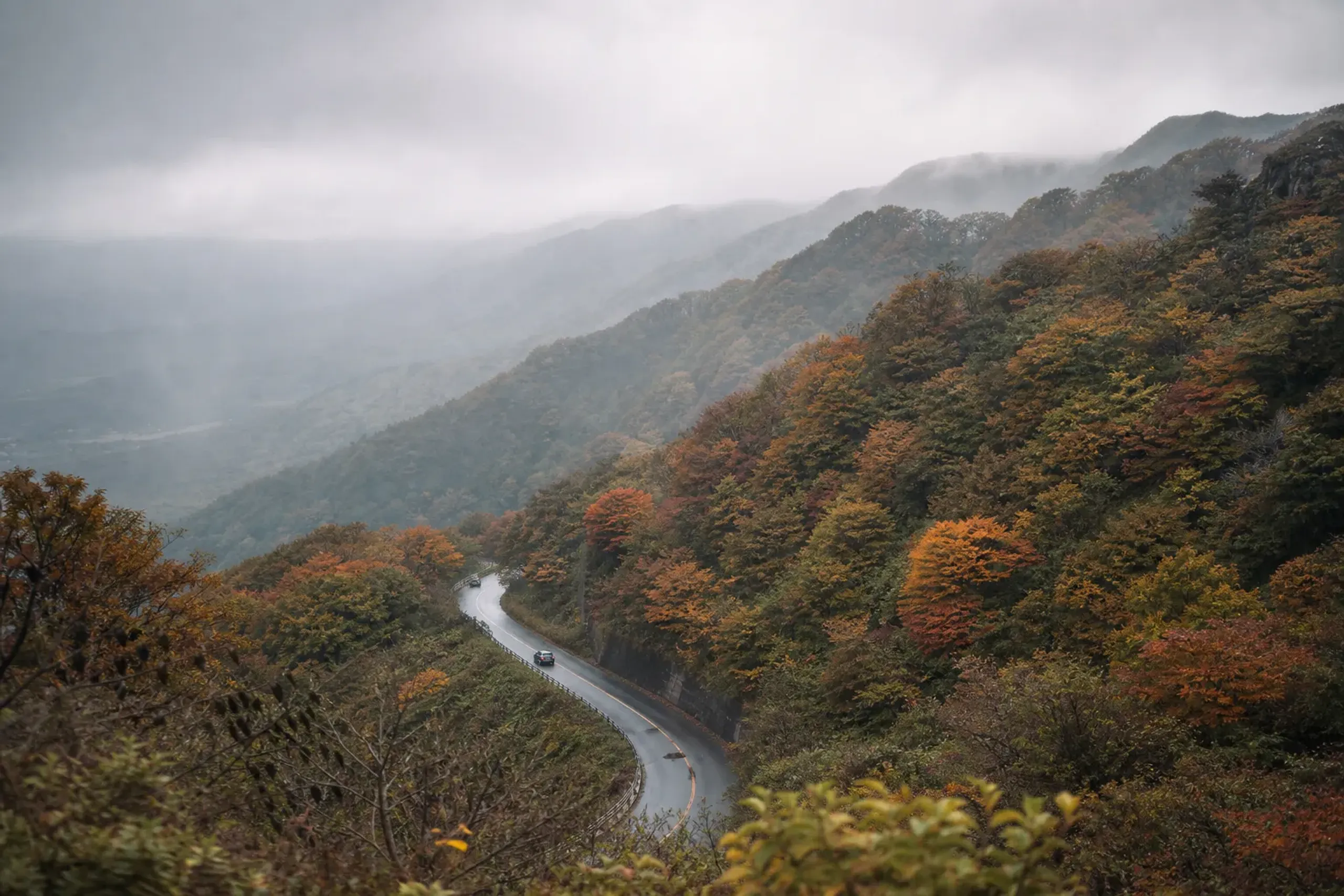 Picturesque autumn scene in Nikko, Japan featuring vibrant foliage and cars against mountains. — Photo by Maheshwaran Shanmugam on Pexels