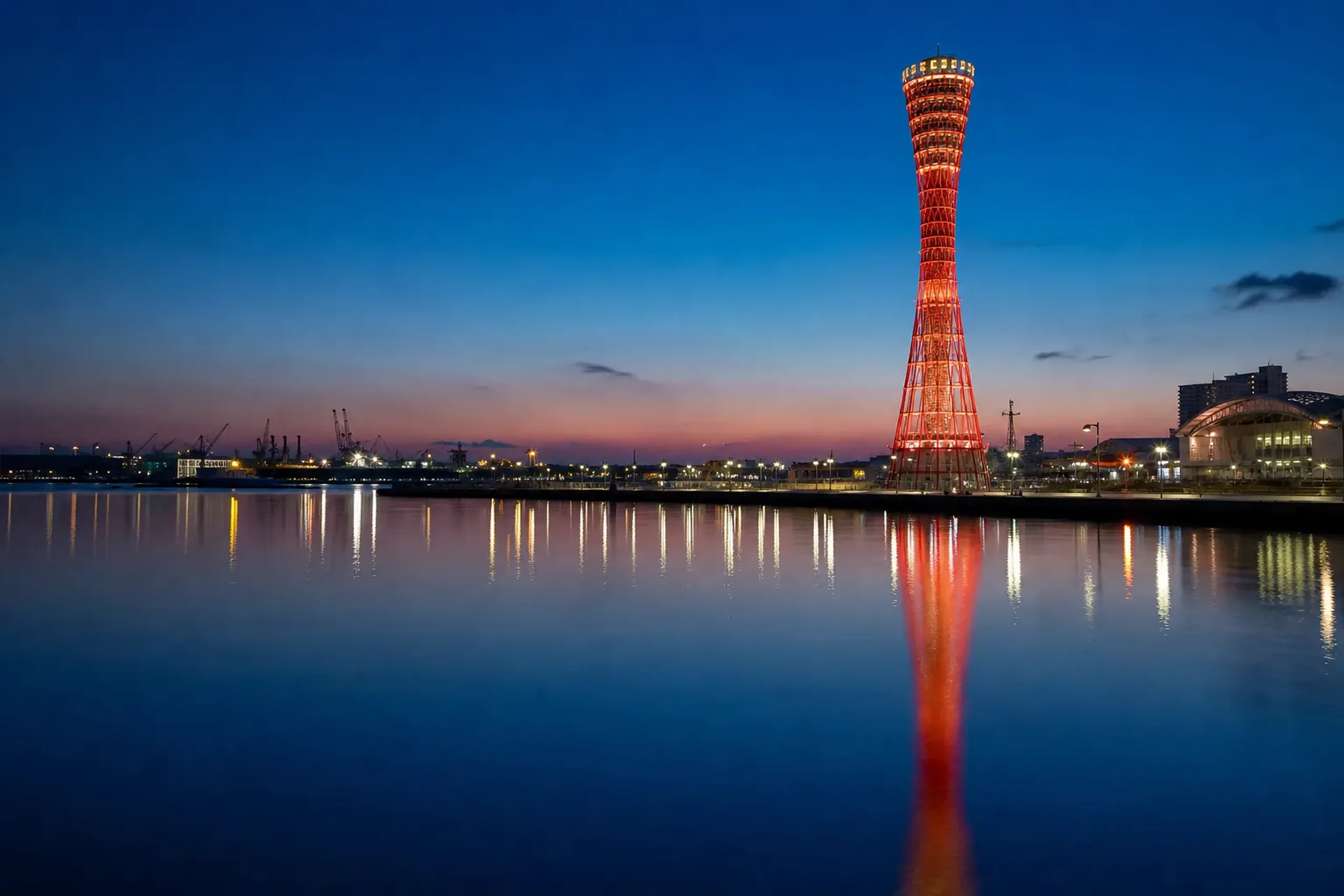 Kobe Port Tower reflecting in the waterfront harbor at twilight.
