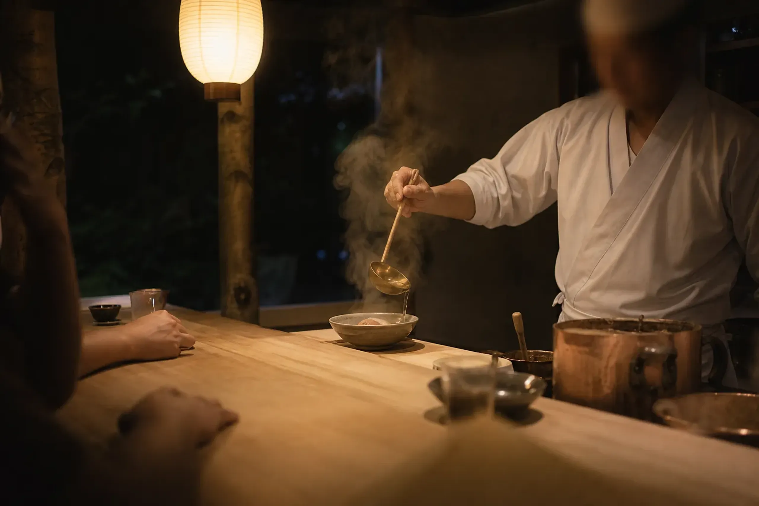 Small wooden ramen counter with chef working close to a handful of guests in Kyoto