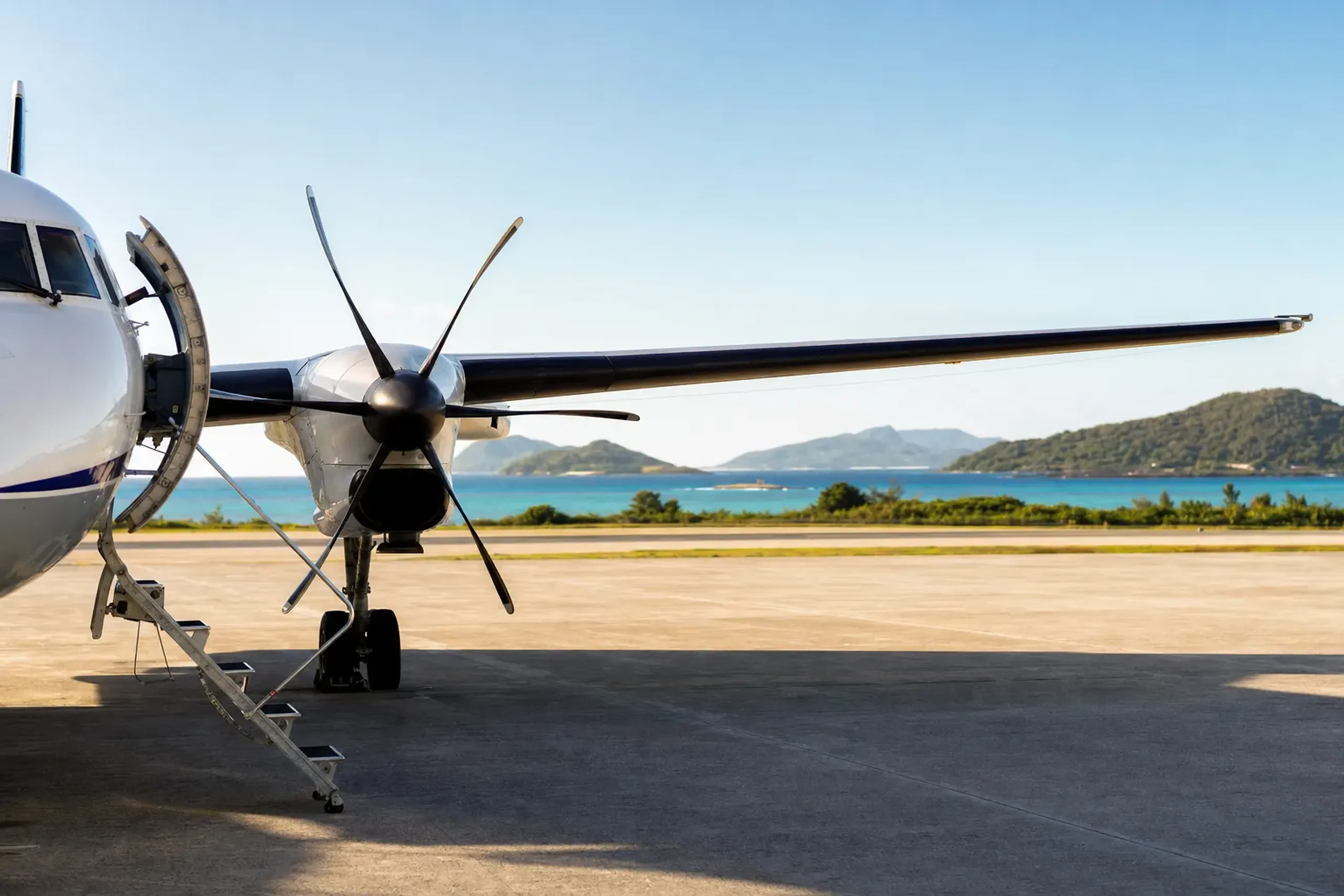 Small aircraft at Kume Island airport with turquoise sea in the background