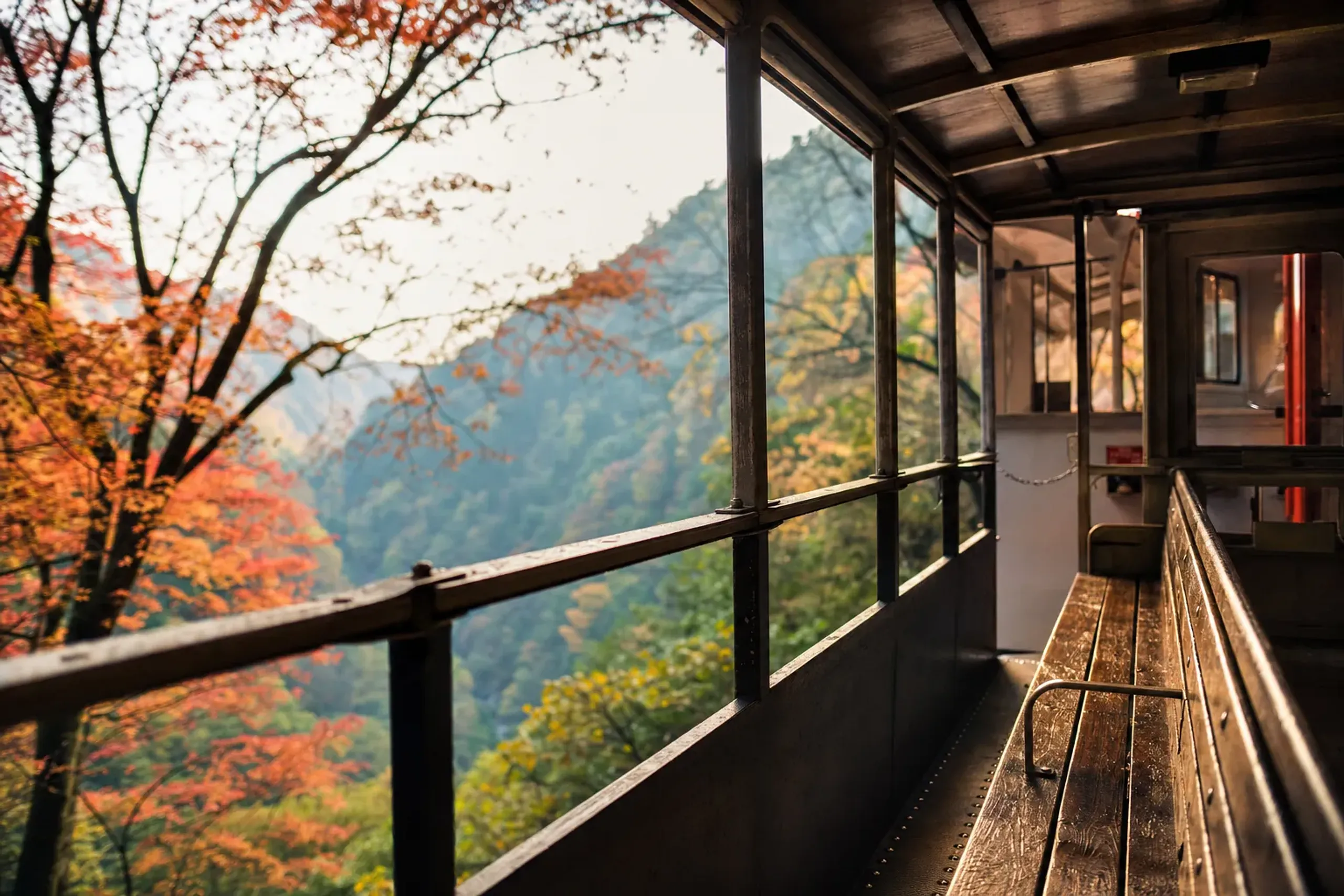 A windowless open-air sightseeing car of the Kurobe Gorge Railway with iron floor, wooden bench, and low guardrail, the gorge open to the air