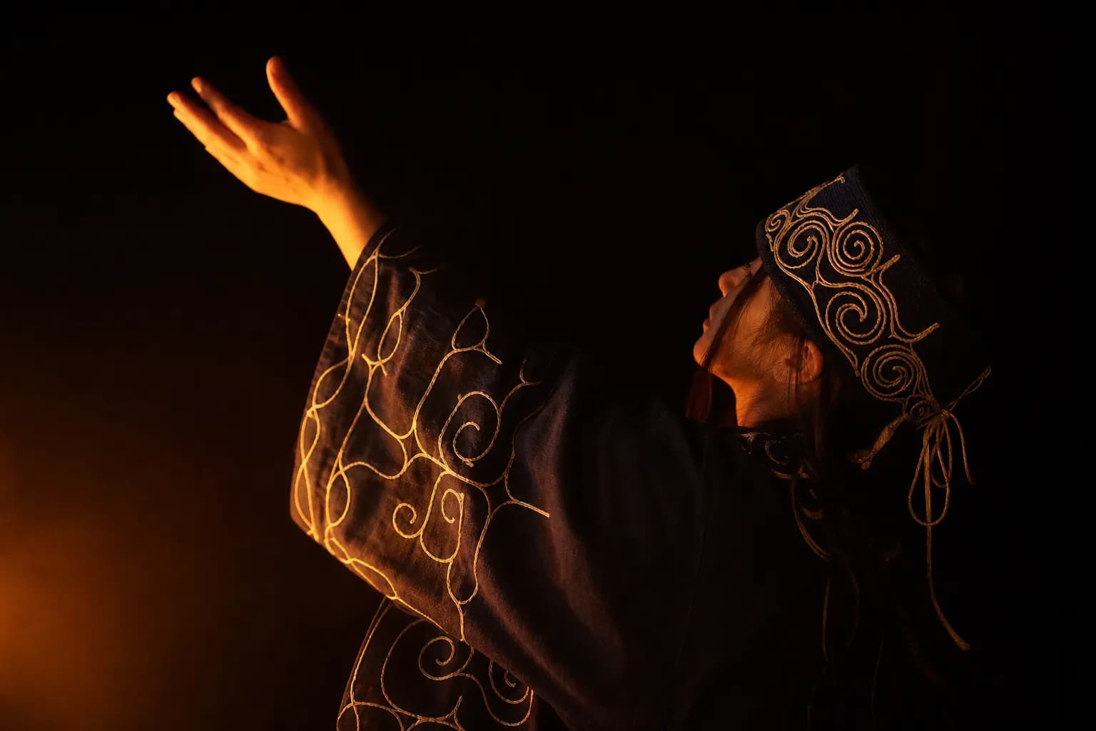 A close-up photograph capturing a traditional Ainu dancer in intricately embroidered robes Moving gracefully before a glowing fire, showcasing the vibrant patterns and spiritual indigenous heritage of Hokkaido.