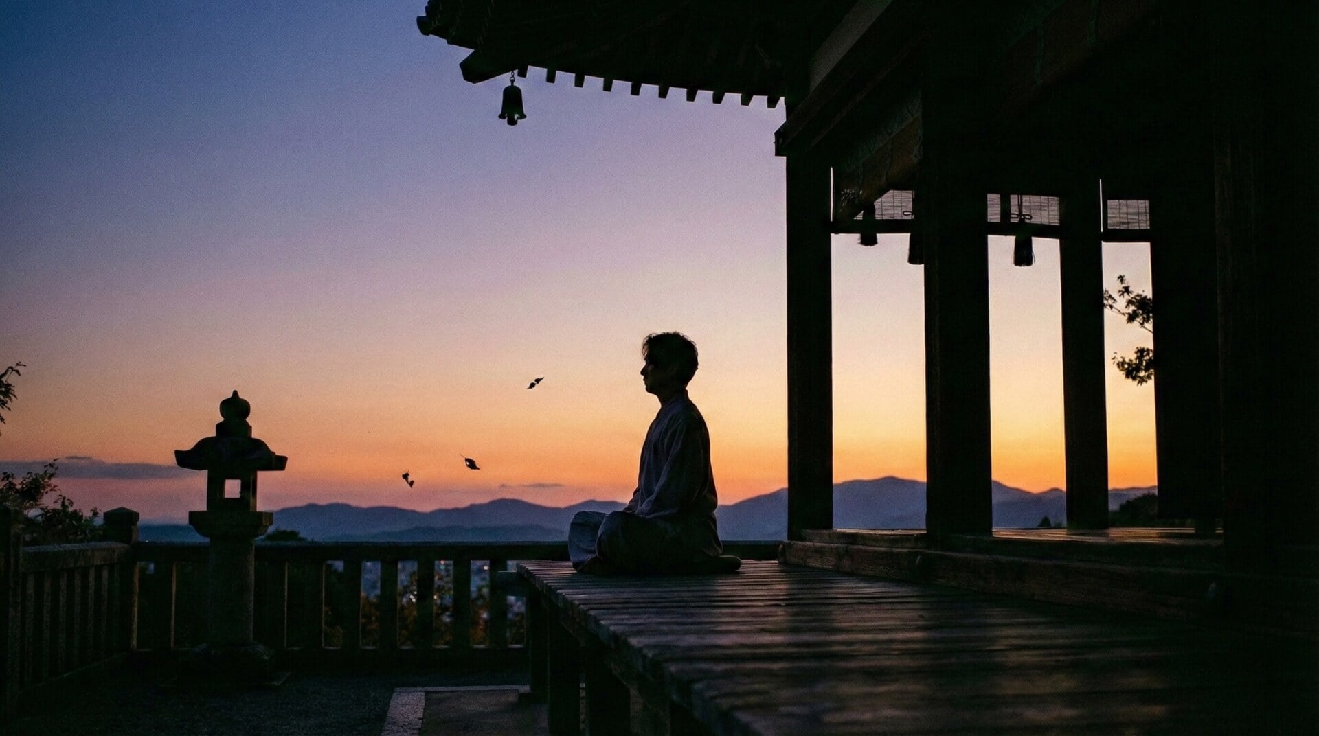A person meditating on a wooden veranda of a Japanese temple during the quiet hours of sunset.