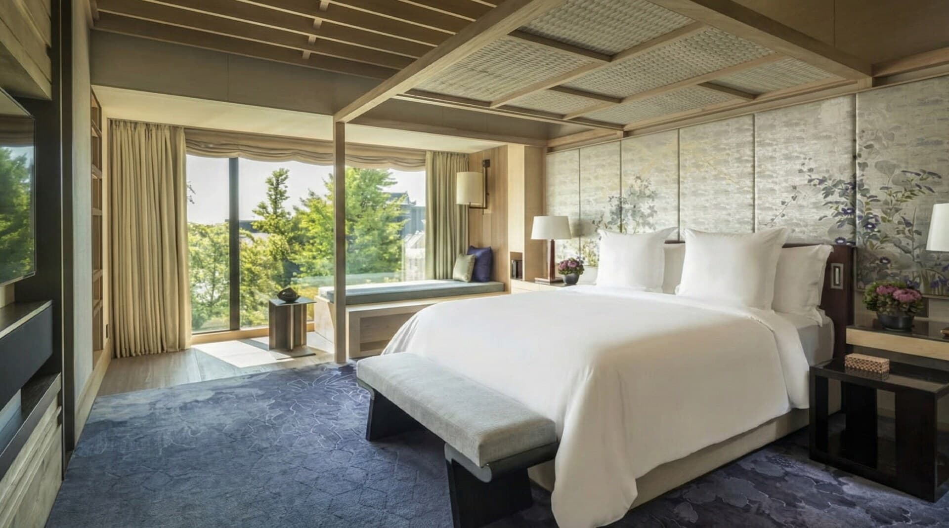 The main bedroom of the Presidential Suite with a view of the garden through floor-to-ceiling windows.