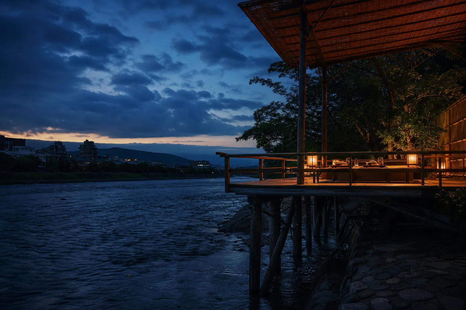 Elevated wooden dining platform over the Kamogawa river in Kyoto at twilight.
