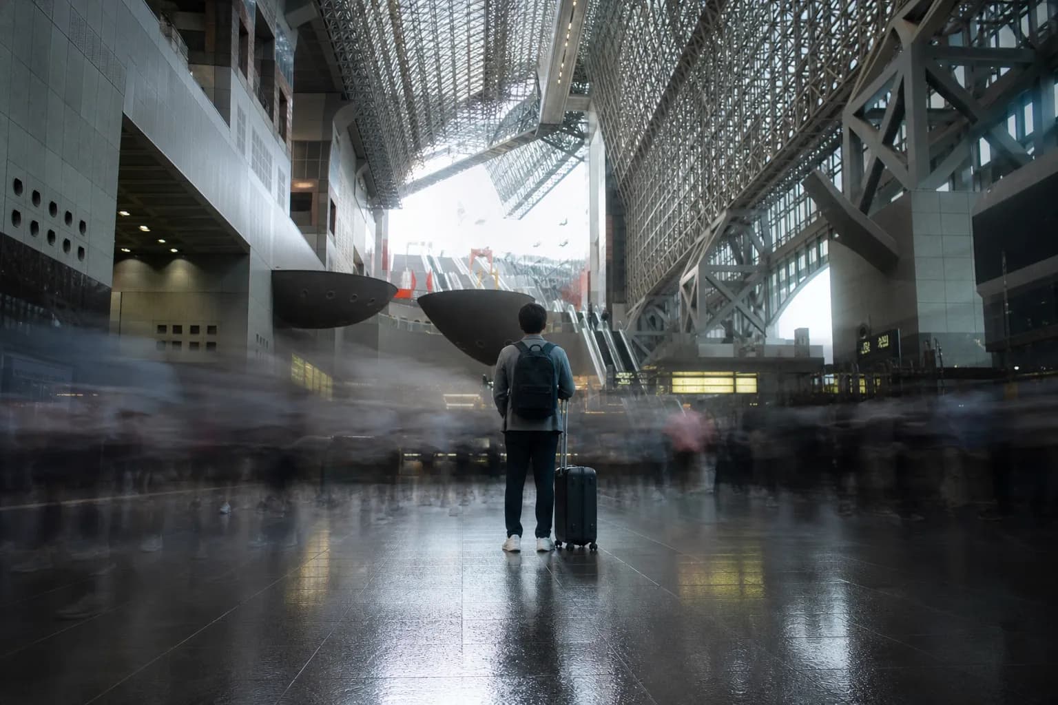 A sophisticated long-exposure photograph capturing the dynamic motion of commuters at Kyoto Station, where blurred figures signify the intense energy and volume of morning peak travel times.