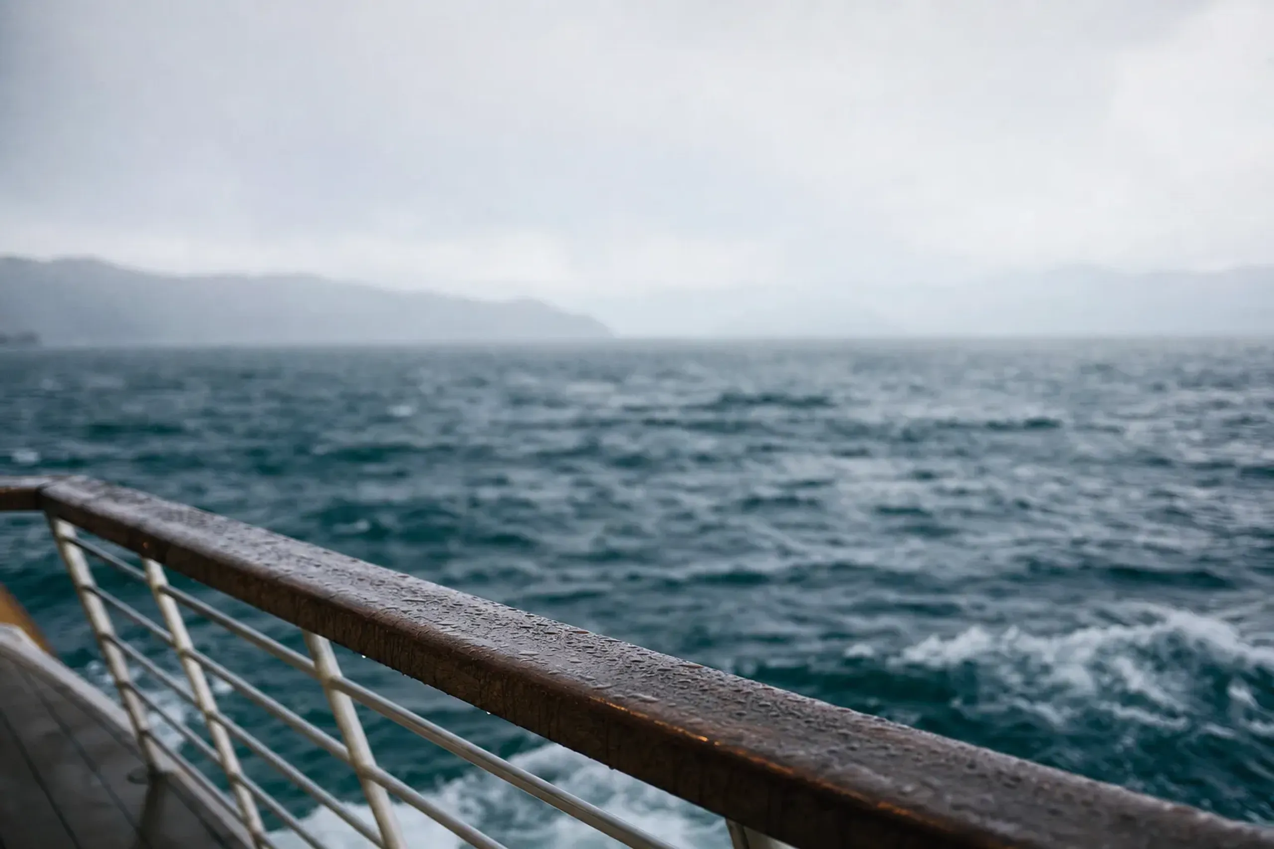 The open northern basin of Lake Biwa seen from the deck of a cruise boat, the far shore vanishing into haze with waves building across the wide water