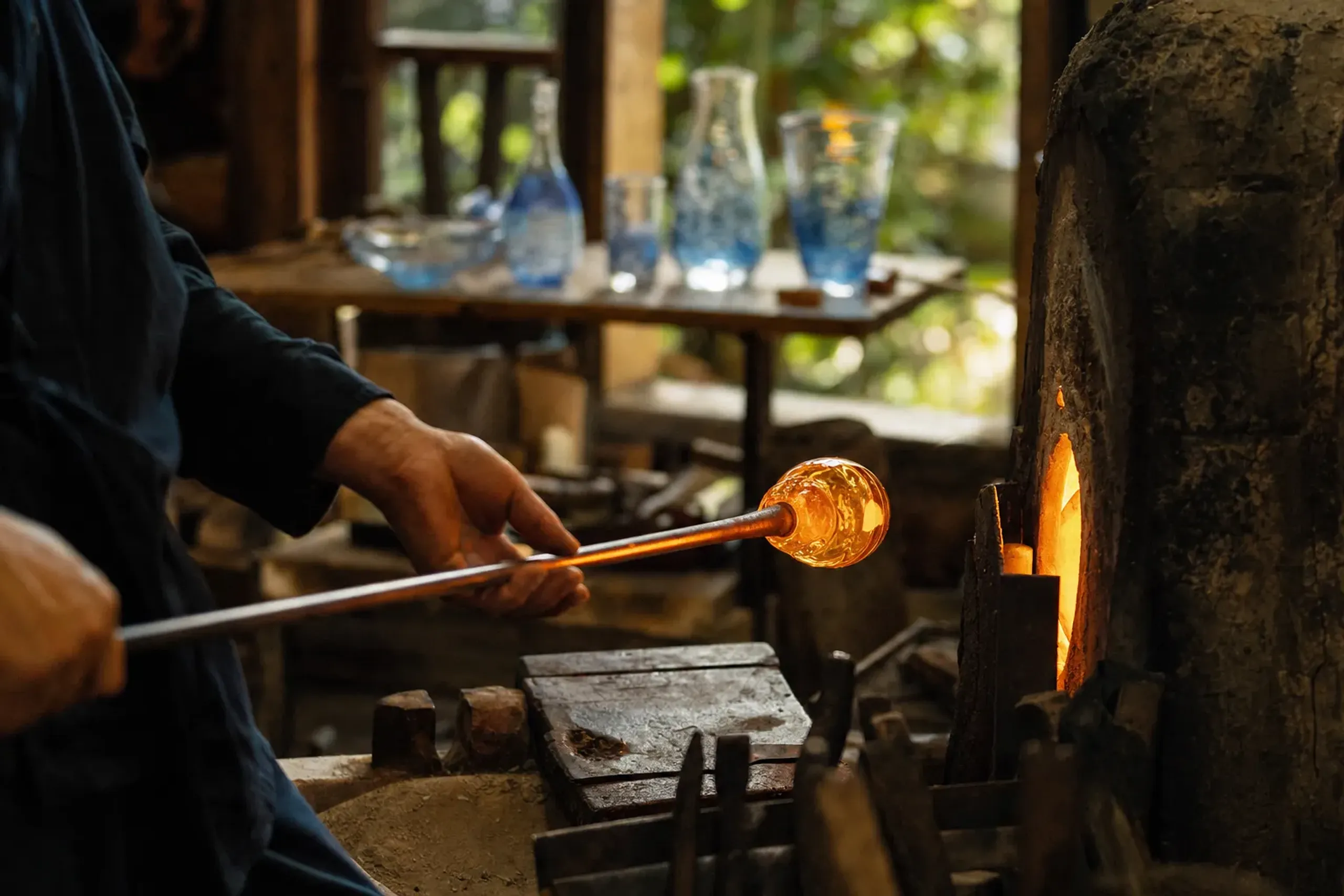 A glassblowing studio in Nagahama's glass art district, molten glass being shaped and finished craft glassware displayed on shelves