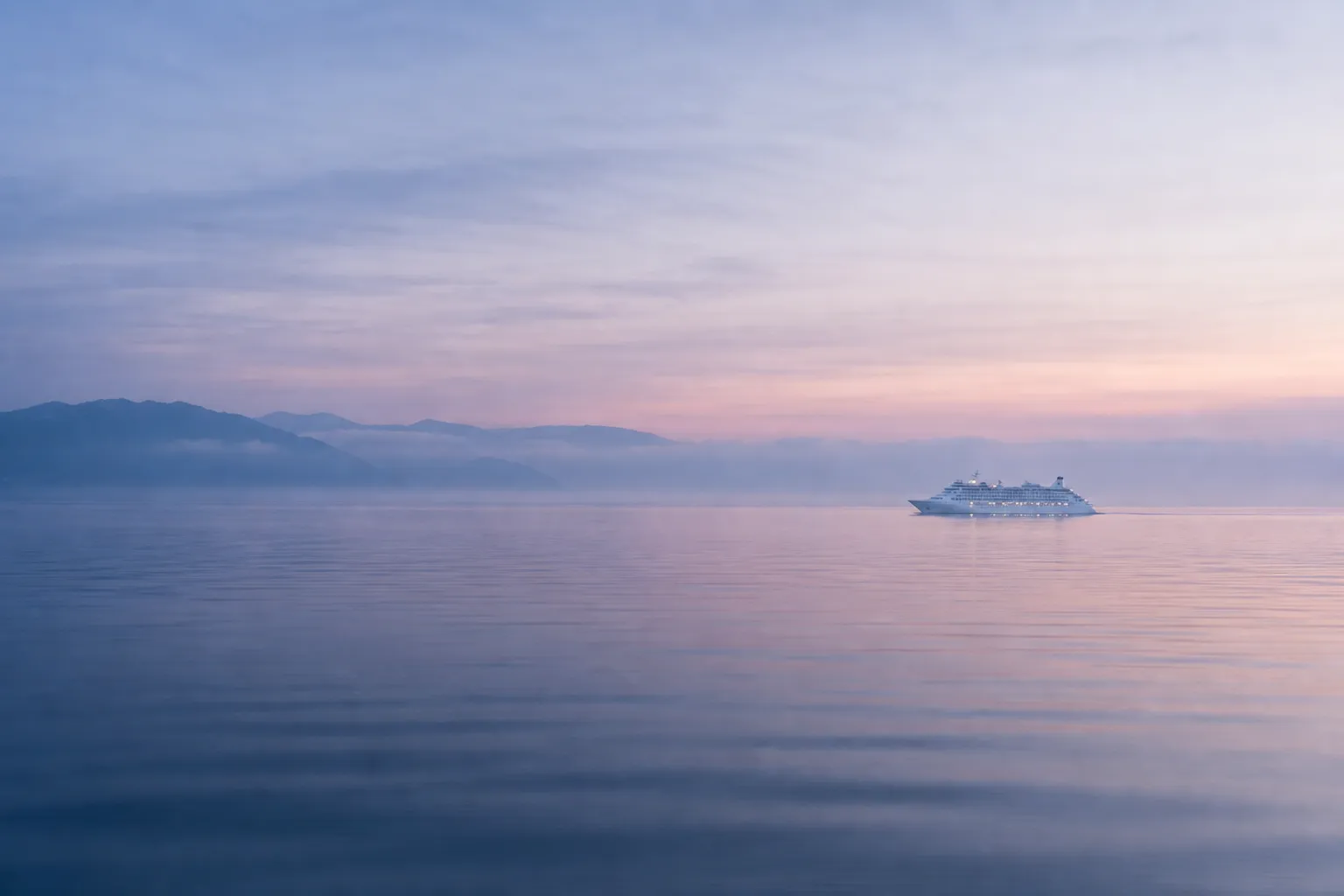 Small luxury cruise ship sailing along Japan’s coast in calm morning light