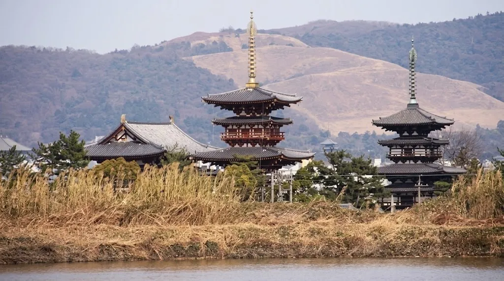 The pagodas of Yakushi-ji temple rising above winter reeds with the Nara hills behind