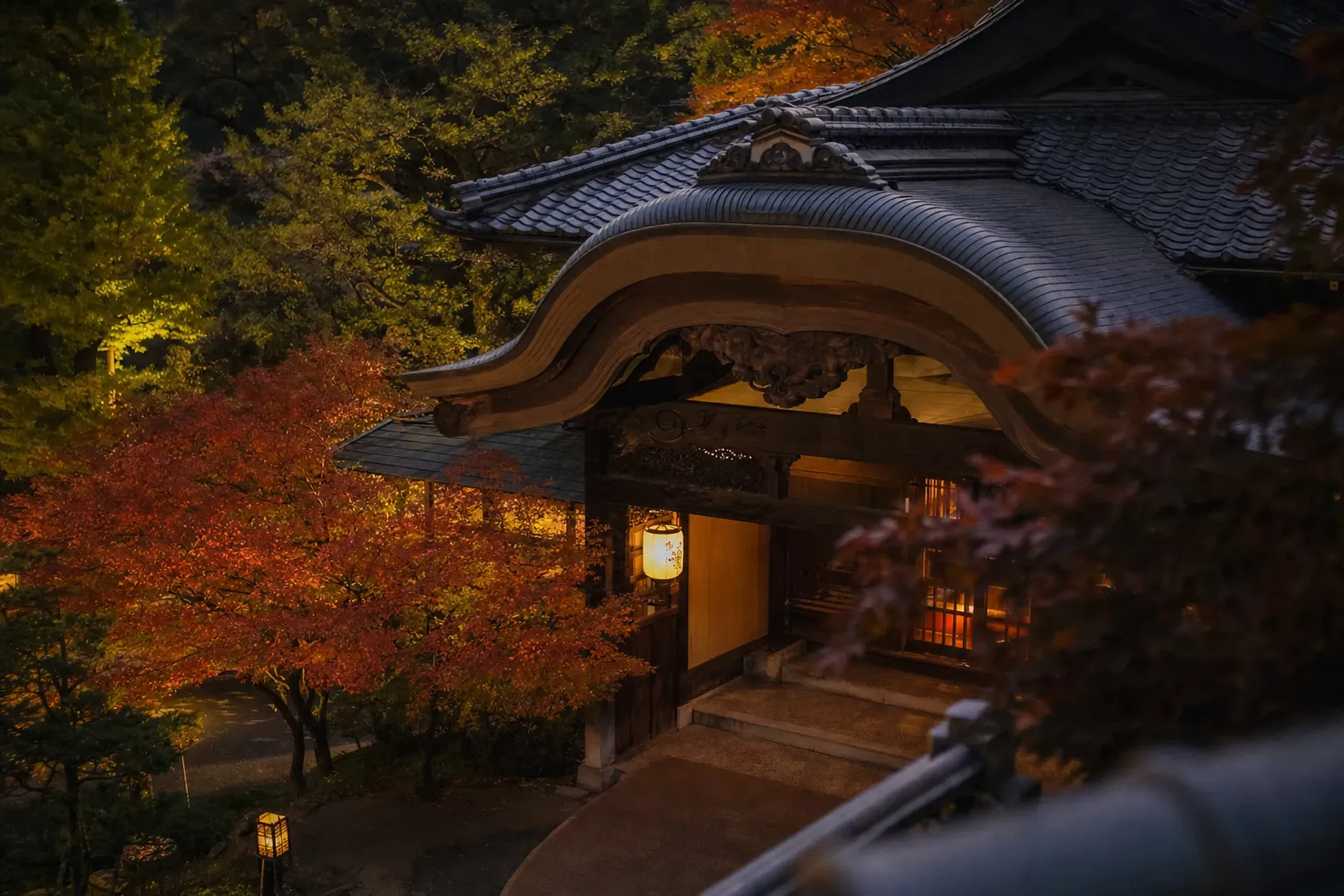 The karahafu-irimoya-zukuri roof entrance of Mikawaya's honkan, its sweeping cusped gable of dark timber and tile catching afternoon light in the Hakone highlands