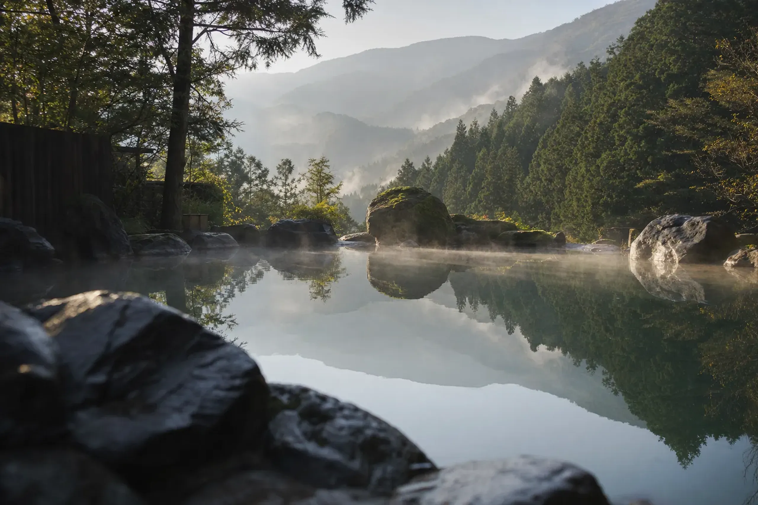 The clothing-free open-air onsen at Mori no Yu, its rock-lined pool of clear water framed by the wooded slopes of Hakone's outer-ring mountains