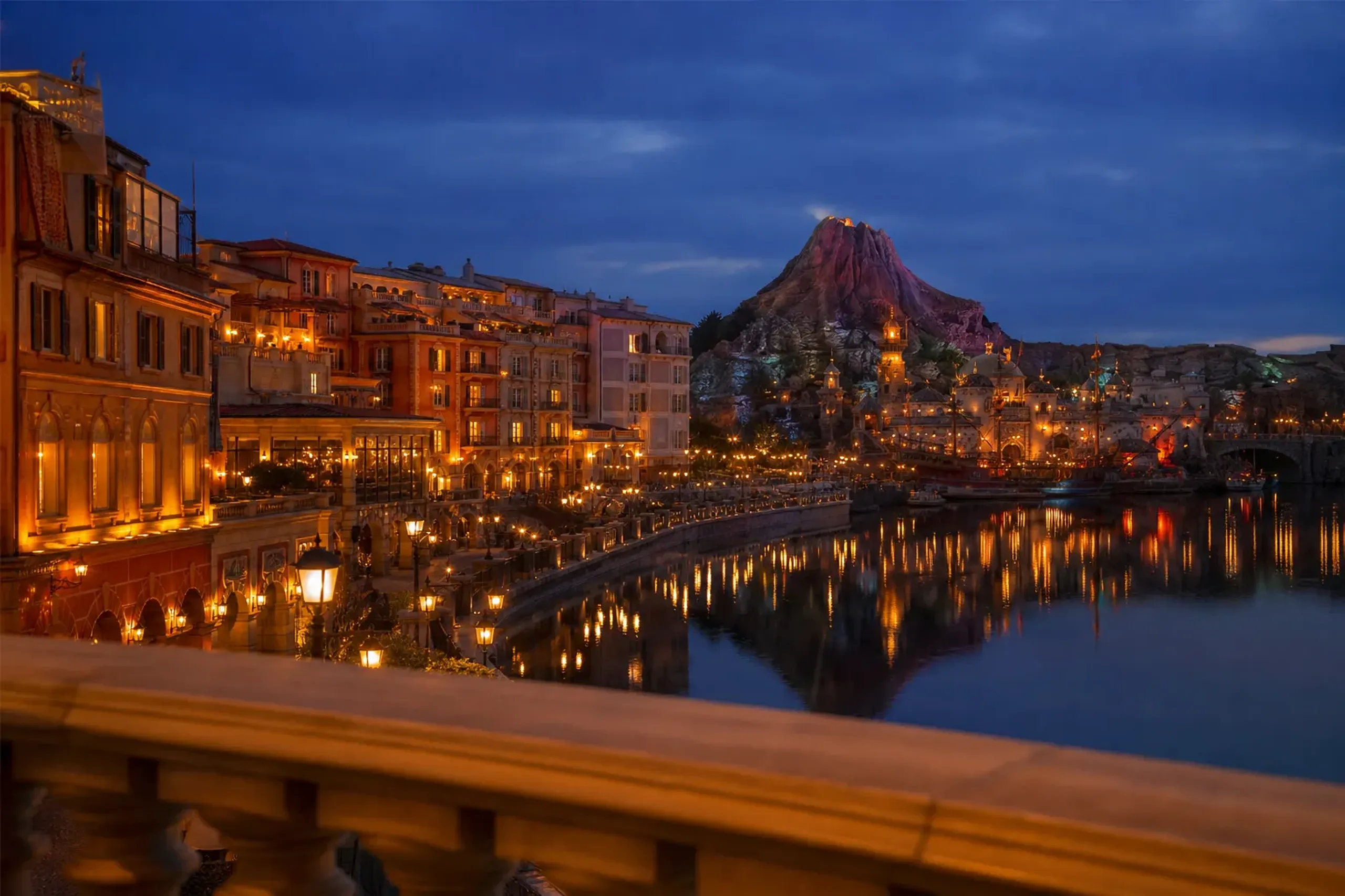 Night view over Porto Paradiso harbor at Tokyo DisneySea with buildings lit and reflections on the water