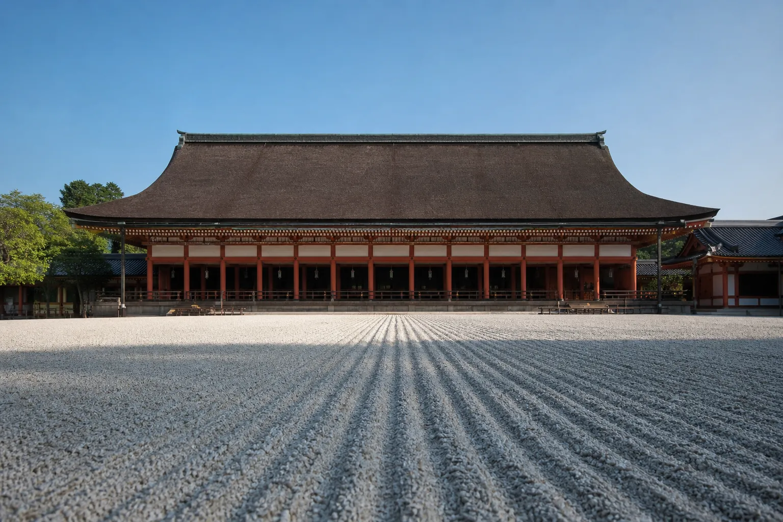 A wide, symmetrical view of the Kyoto Imperial Palace's elegant wooden Main Hall, featuring sweeping roofs, vermillion pillars, and an impeccably raked white gravel courtyard in the foreground.