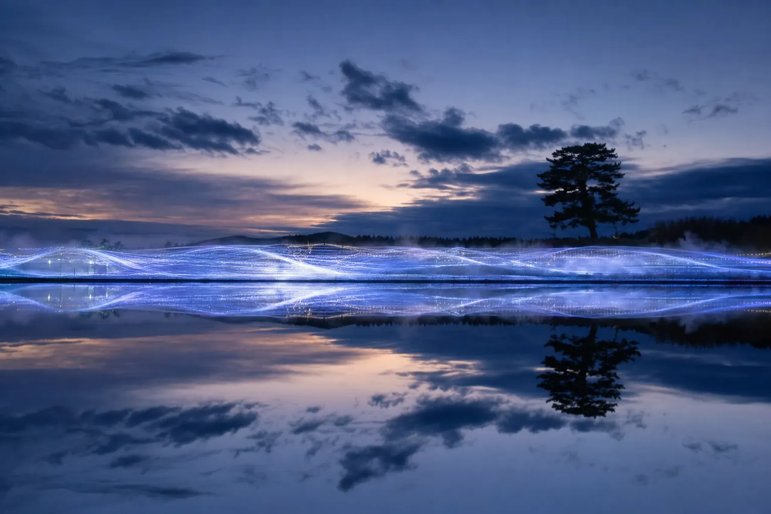 The Hikari no Taiga river-of-light water-surface illumination at Nabana no Sato reflecting on a still pond surface at dusk