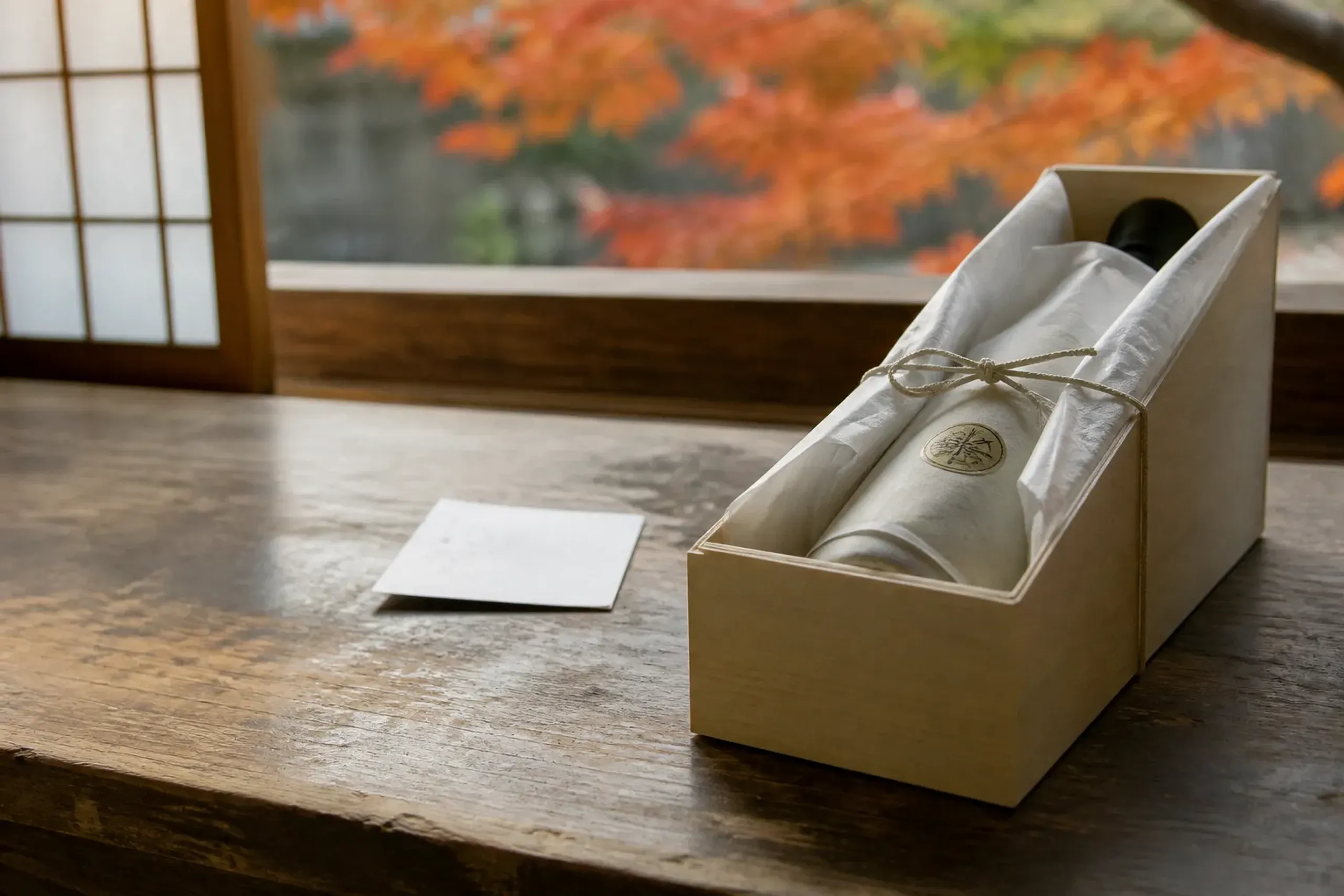 A boxed bottle of Nada sake packed in protective wrapping at a brewery storefront counter, ready for domestic shipment