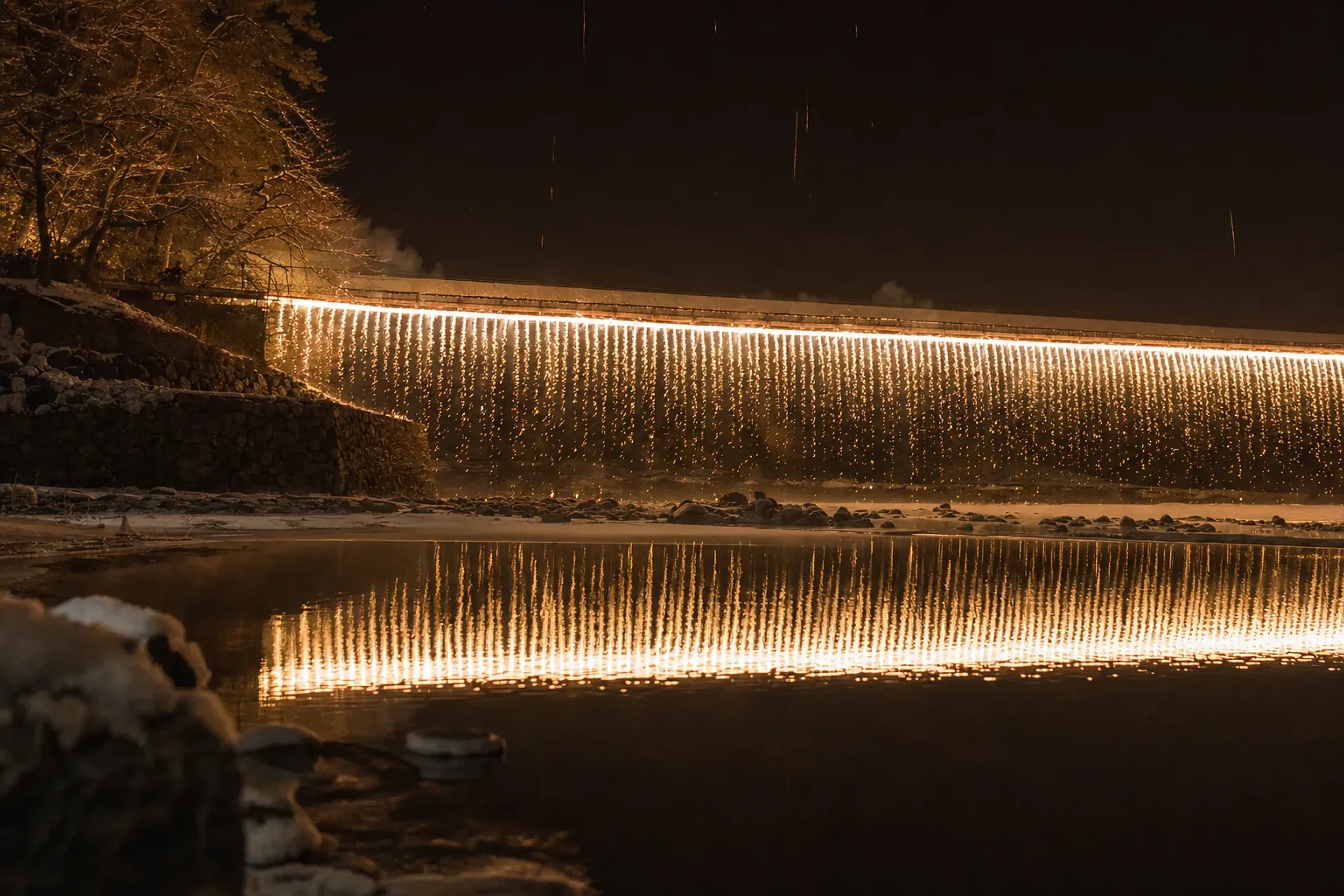 the Niagara cascade of fire pouring down from a bridge over the Shinano River toward the dark water