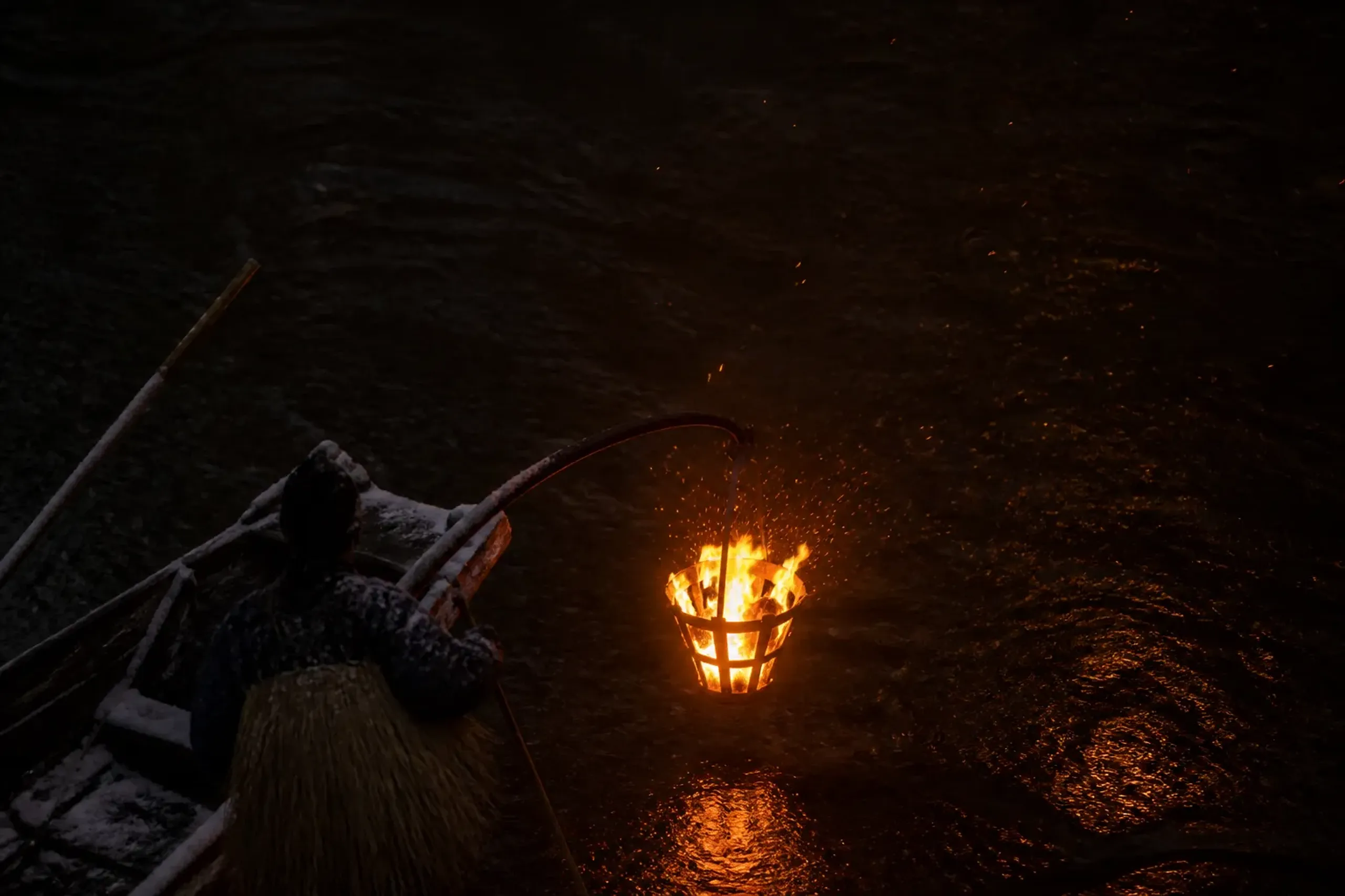 a lit pine torch flaring on the bow of a working ukai fishing boat, sparks rising over the black Nagara River at night