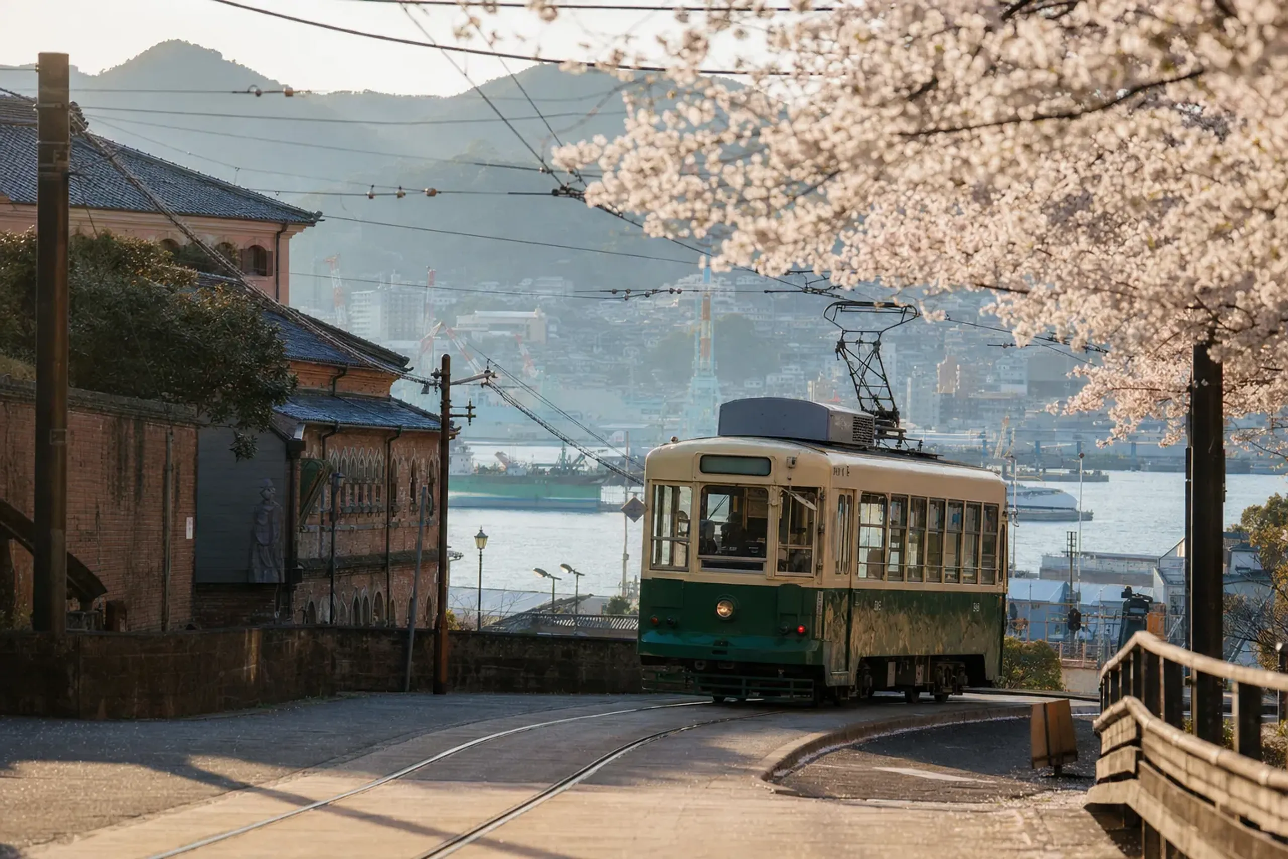 A Nagasaki city tram passing near the Dejima district with harbour views