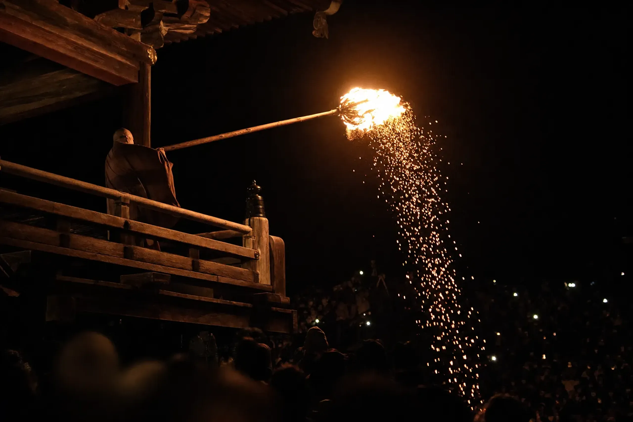 The Omizutori fire ceremony at Tōdai-ji temple in Nara, with monks brandishing enormous flaming torches along the wooden balcony of the Nigatsu-do hall against the night sky