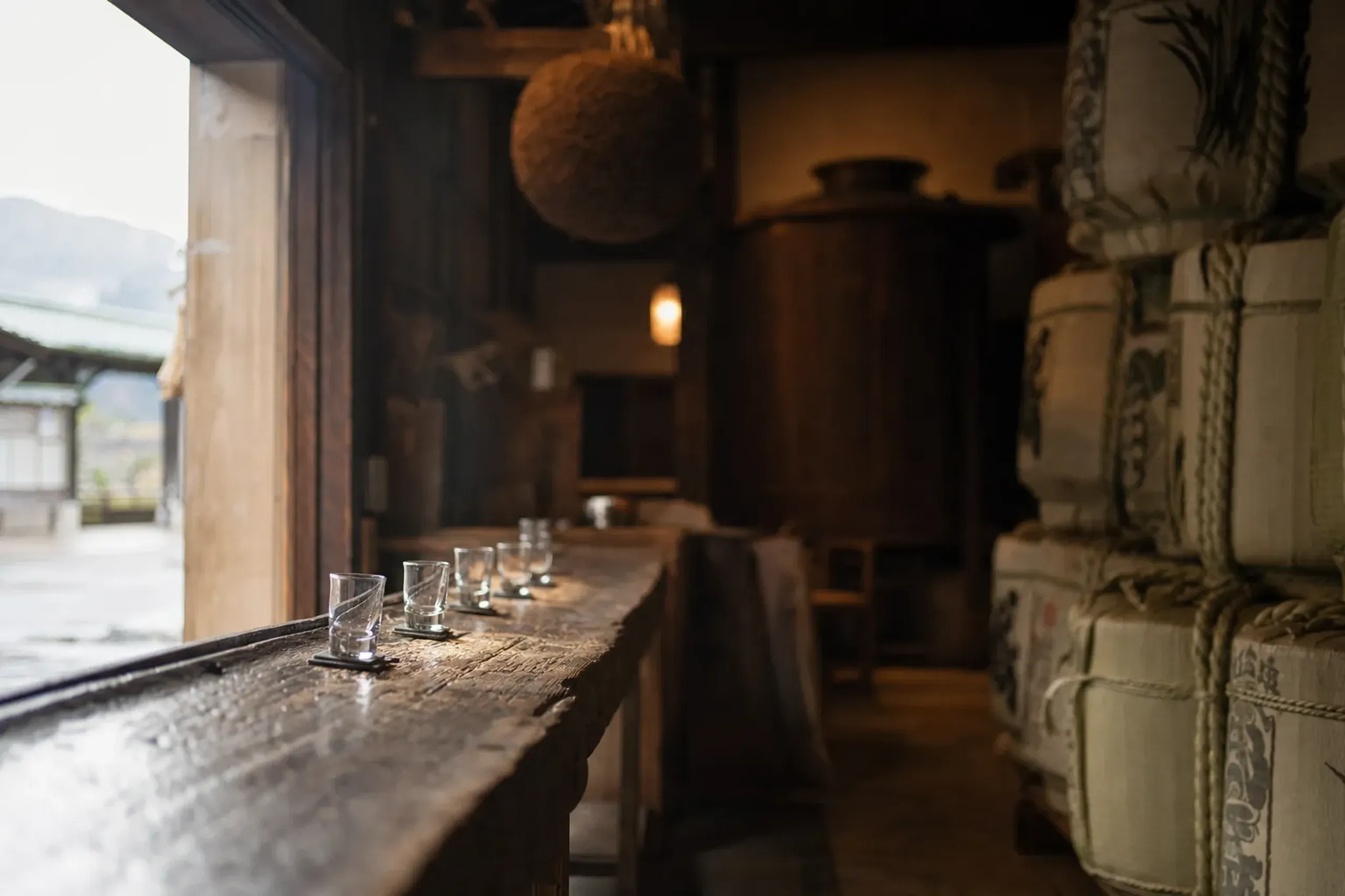 the entrance and wooden tasting counter of Tamagawa Shuzo brewery on Sado Island, sake barrels stacked beside a sliding door