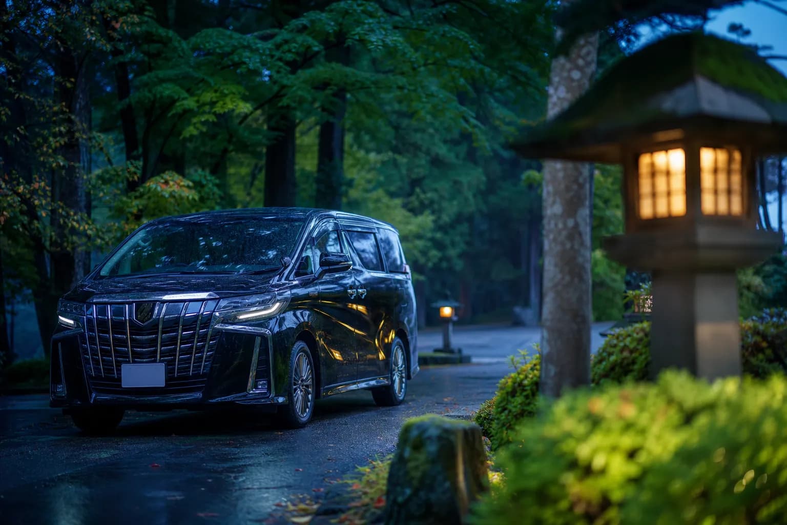 Black chauffeured luxury minivan parked near a forested roadside in Nikko