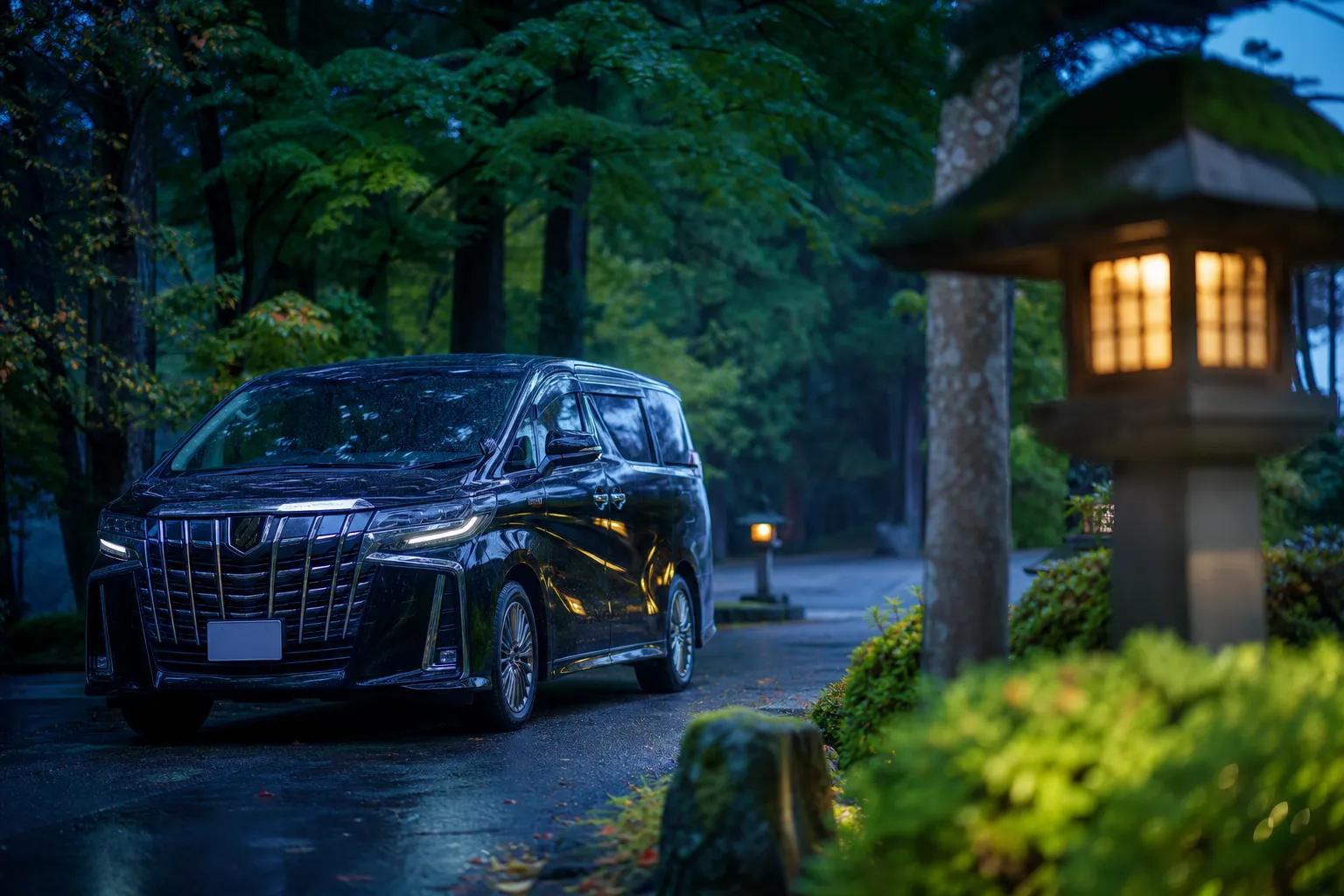 Black chauffeured luxury minivan parked near a forested roadside in Nikko