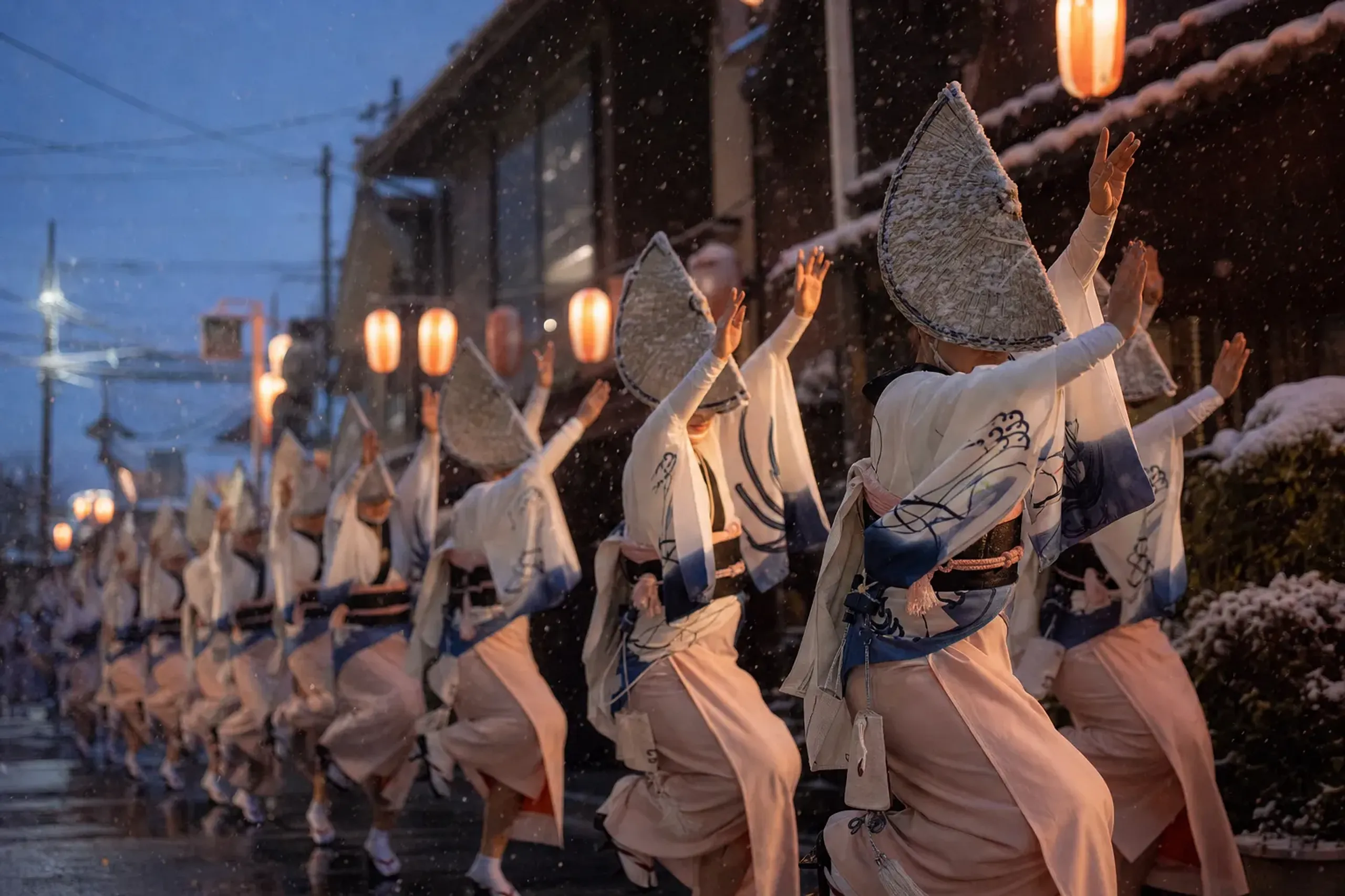 rows of lantern-lit dancers in wide straw amigasa hats mid-step during the Awa Odori festival in Tokushima