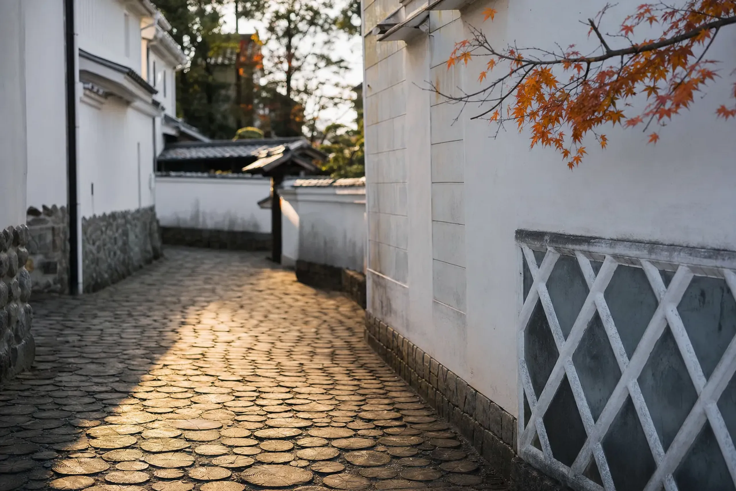 White-walled storehouses and chestnut-wood paving blocks of the Kuri no Komichi path winding through Obuse's compact historic district in autumn light