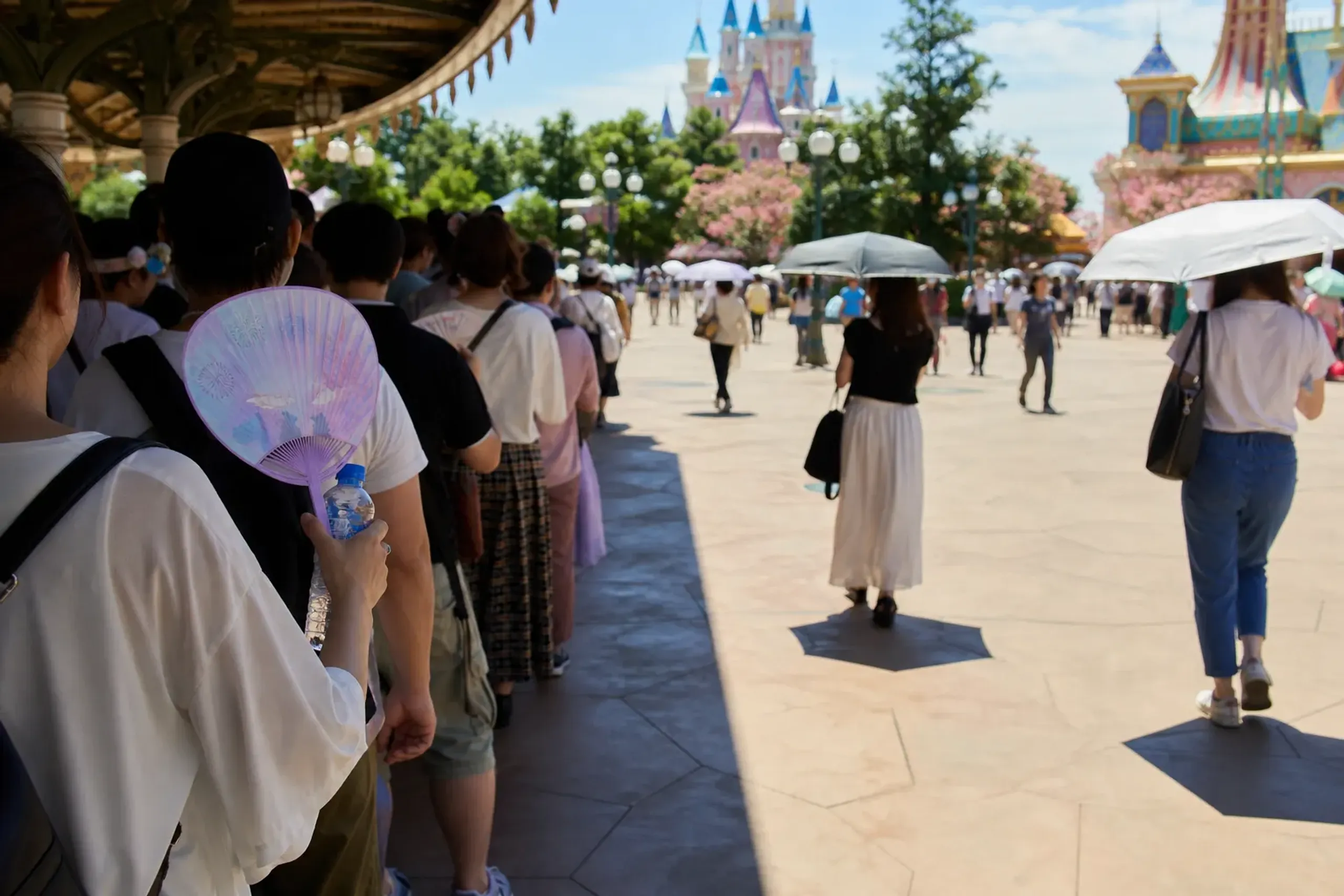 Guests using fans and parasols in a shaded queue on a hot day, illustrating mid-September heat conditions