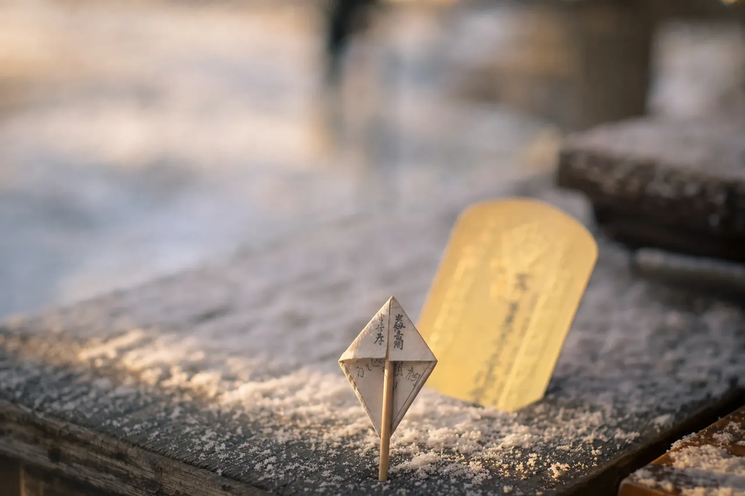 The triangular paper lightning-protection talisman on a bamboo skewer beside a gold prayer tablet issued at Sensō-ji