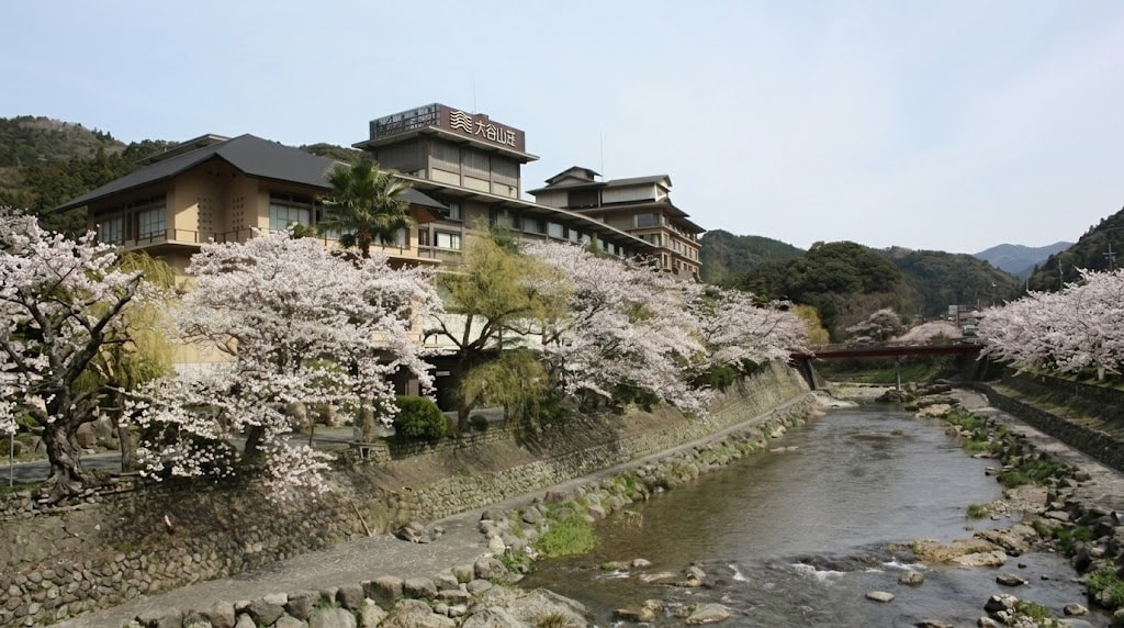 The beautiful exterior of Otani Sanso luxury ryokan in Nagato, surrounded by lush green mountains and the Otozure River.