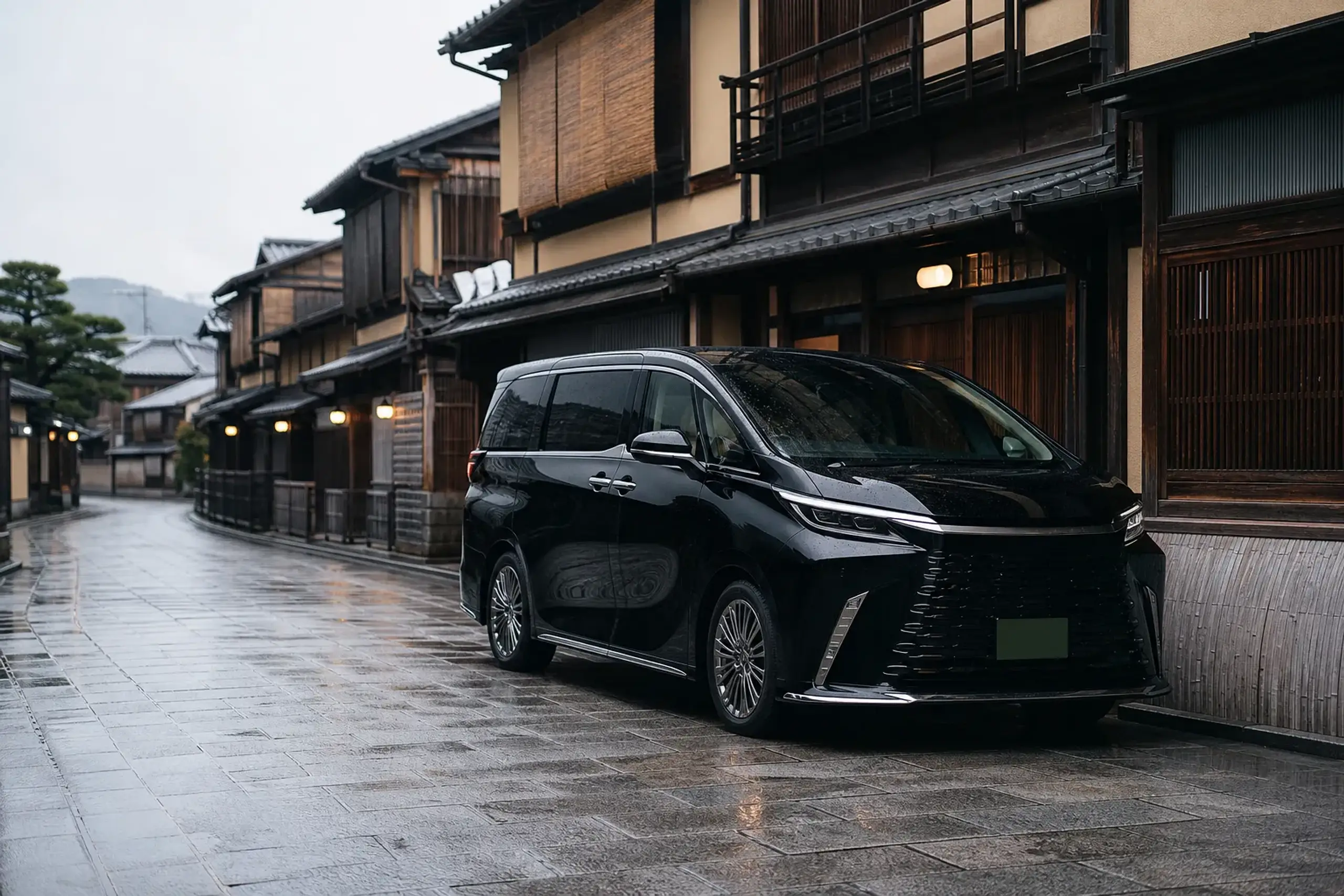 A black Lexus LM 500 with green commercial license plates parked and waiting on a narrow stone-paved lane in Gion, Kyoto, beside traditional wooden machiya townhouses