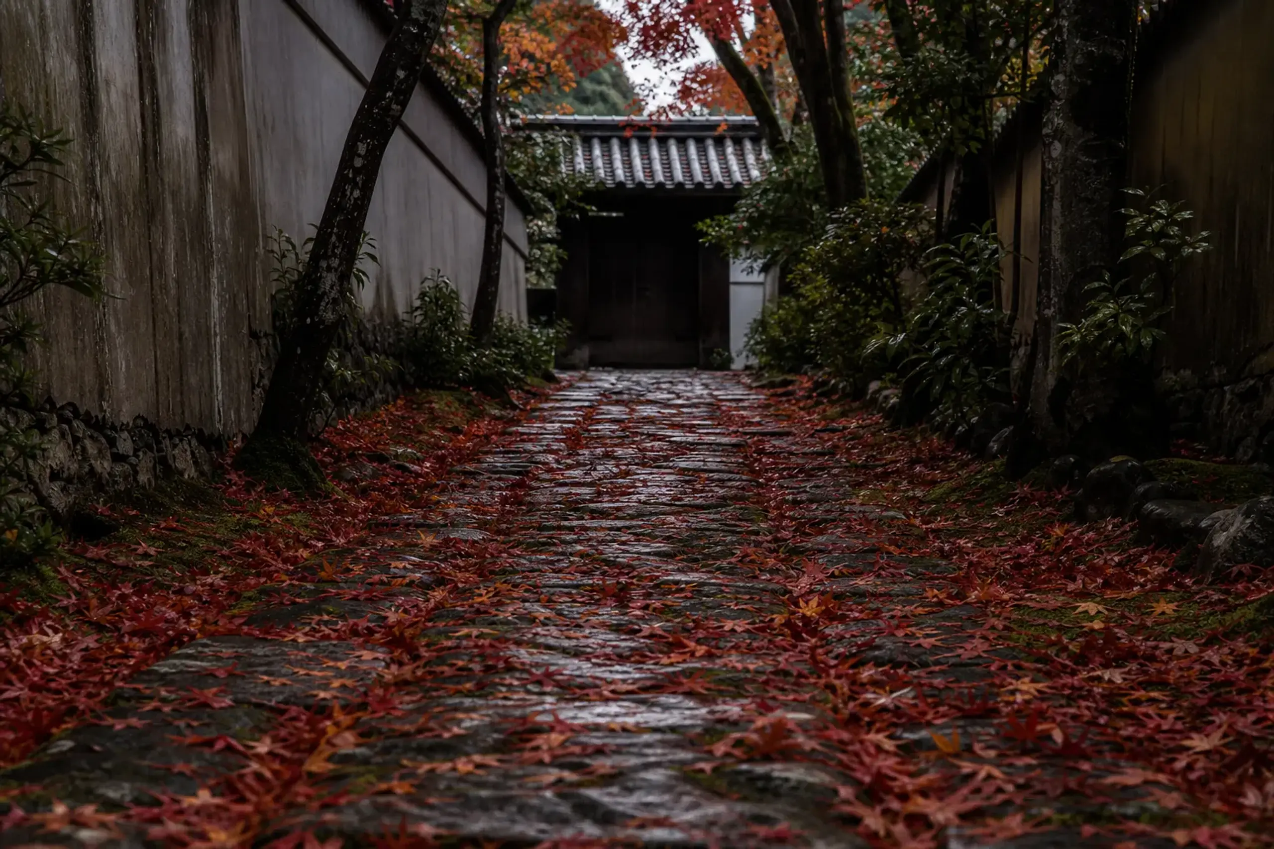 Weathered stone path covered in red maple leaves at a private temple