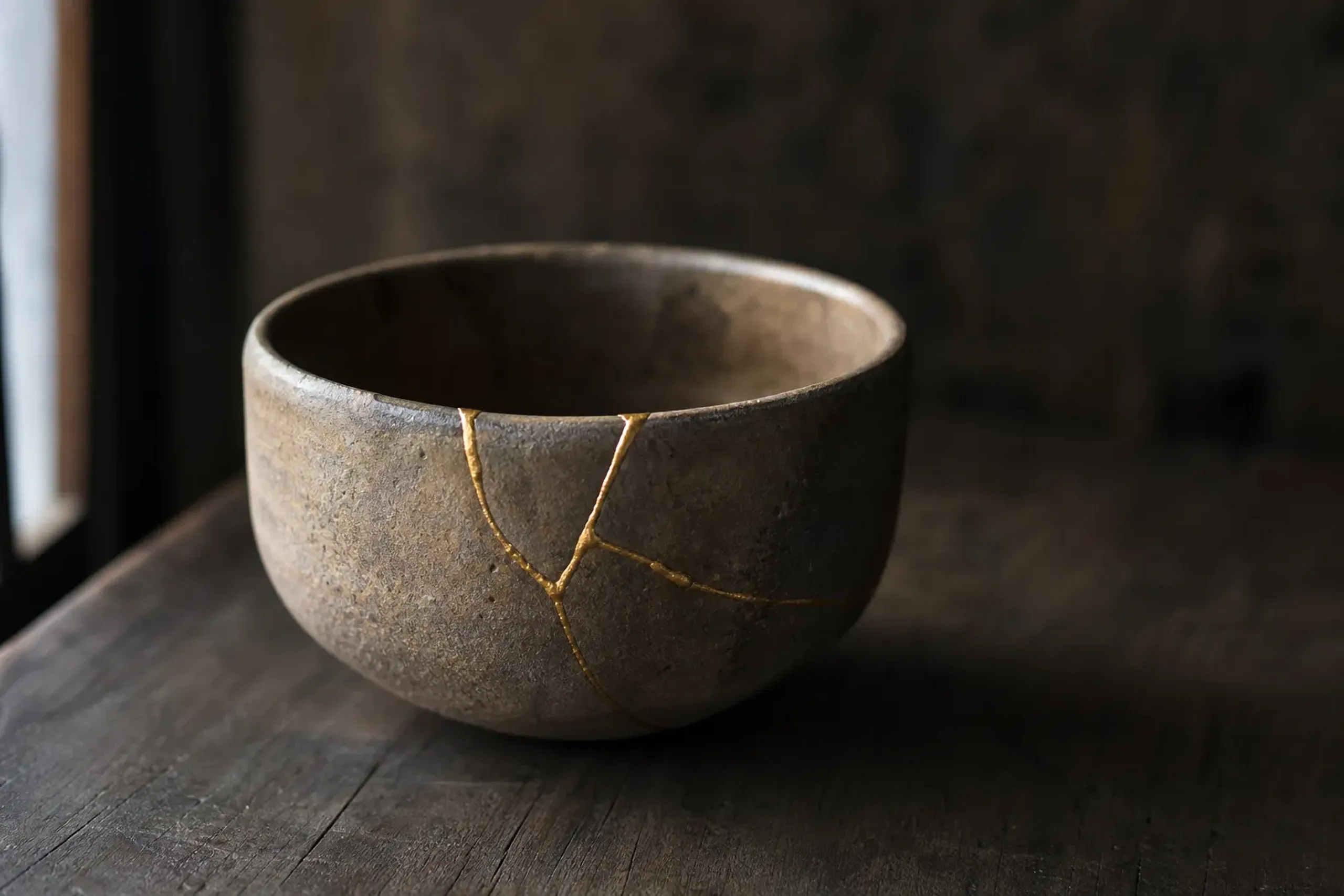 Japanese ceramic bowl mended with gold kintsugi lacquer on a wooden surface