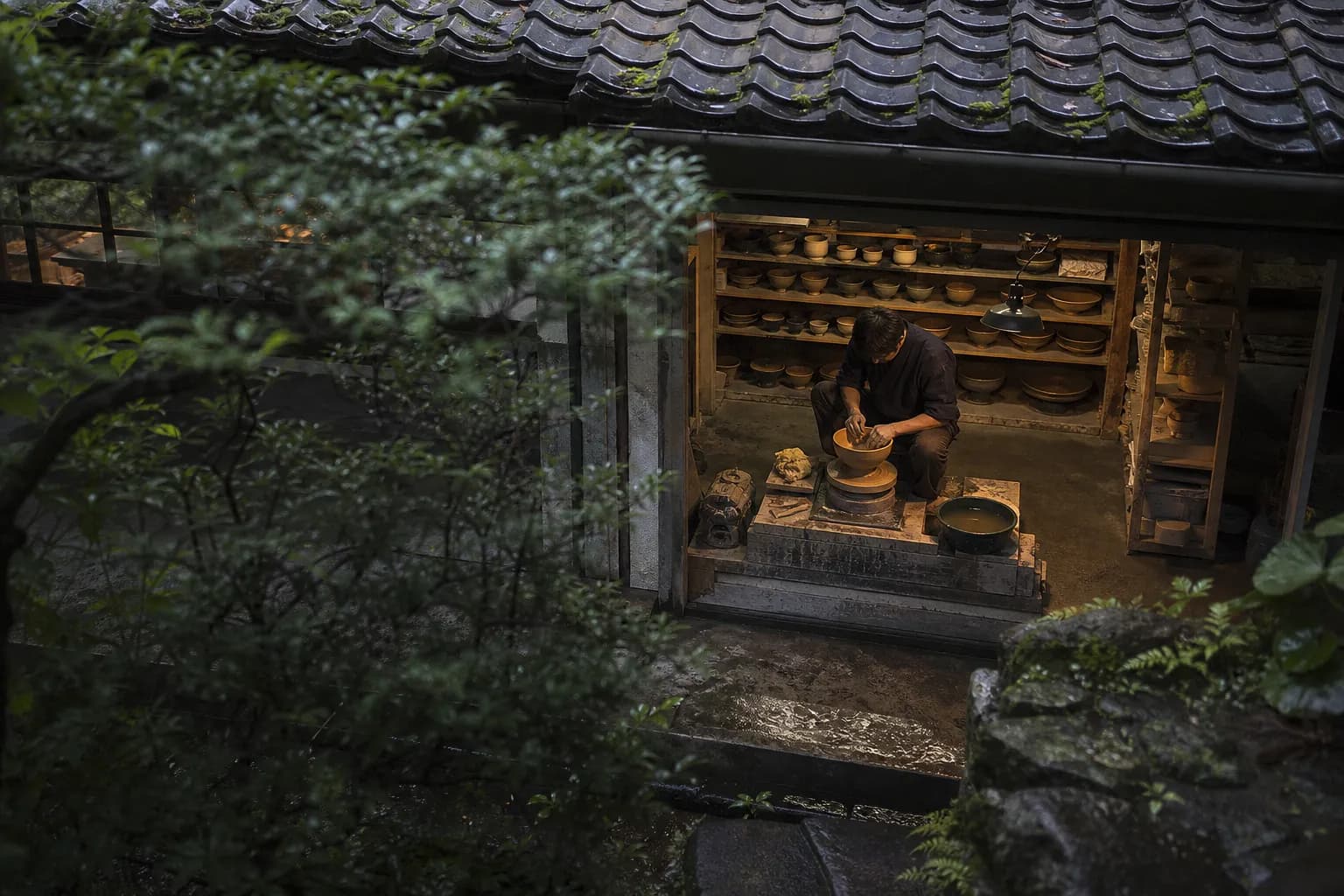 Kyoto ceramic artisan shaping a bowl at the potter's wheel in a private workshop