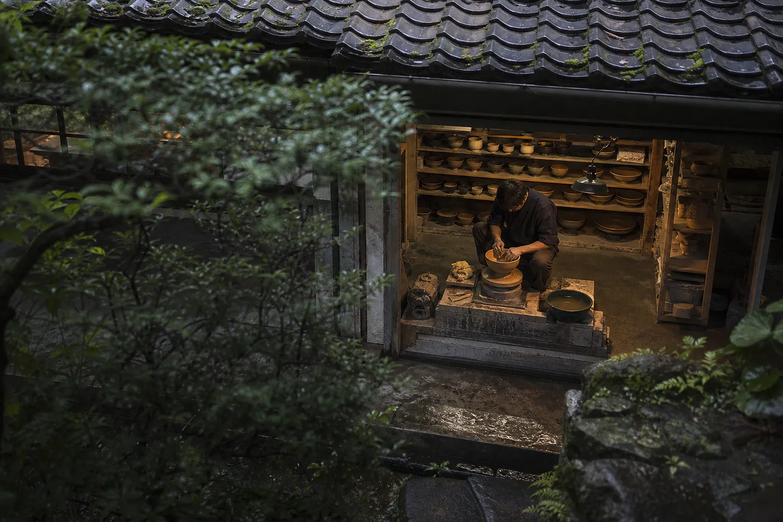 Kyoto ceramic artisan shaping a bowl at the potter's wheel in a private workshop