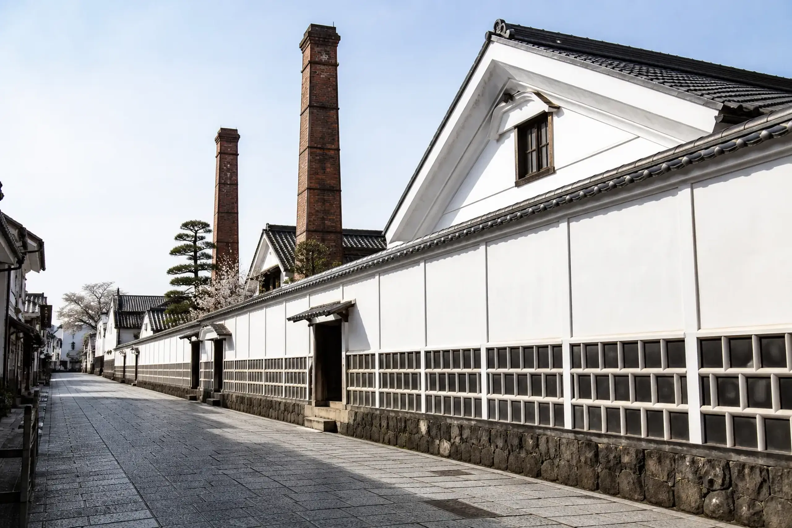 The white plaster kura walls and towering red brick chimneys of the breweries lining Saijō Sakagura-dōri in winter light