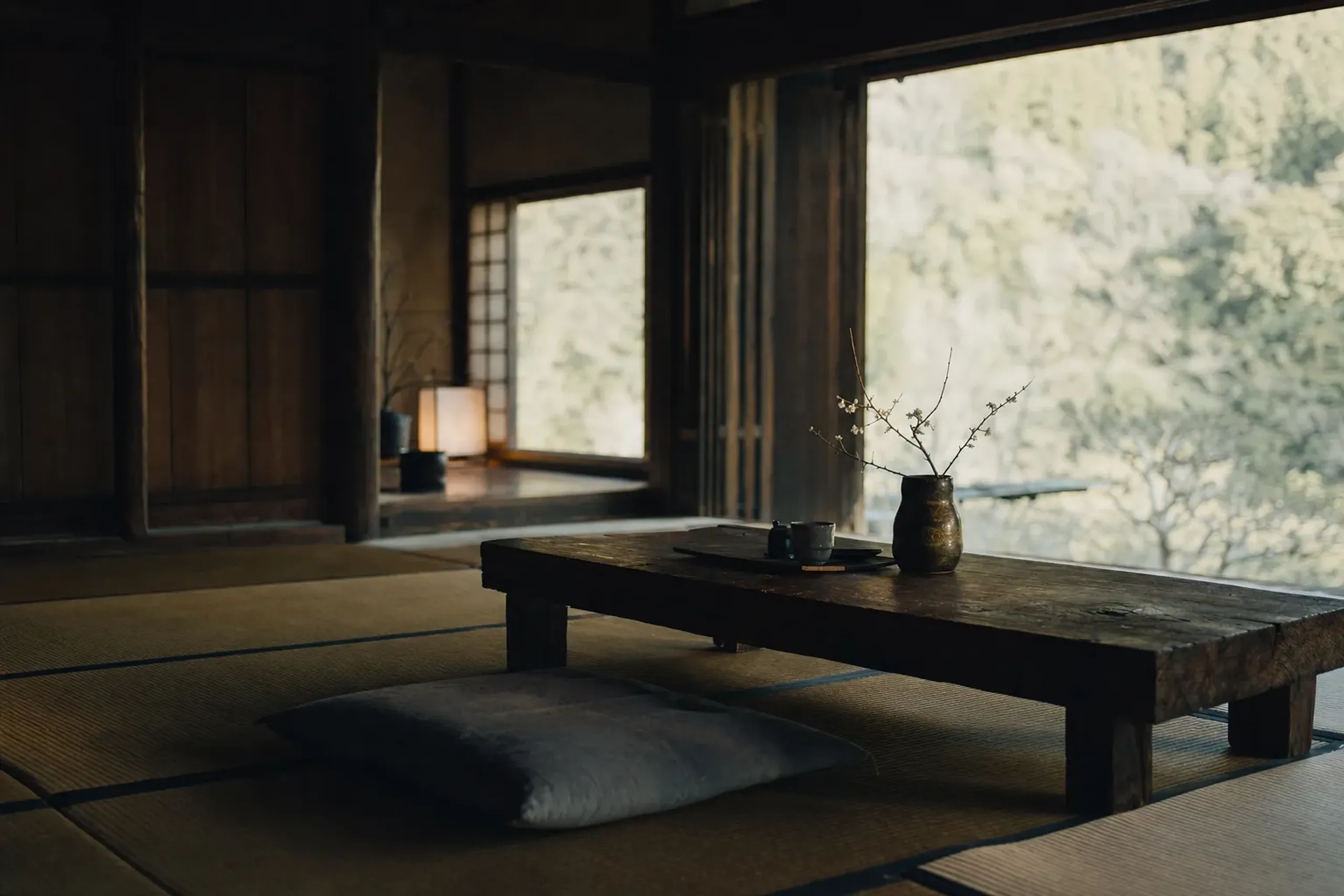 a private minka guest room at Sanso Murata with tatami, low wooden furnishings, and a view of trees through the window