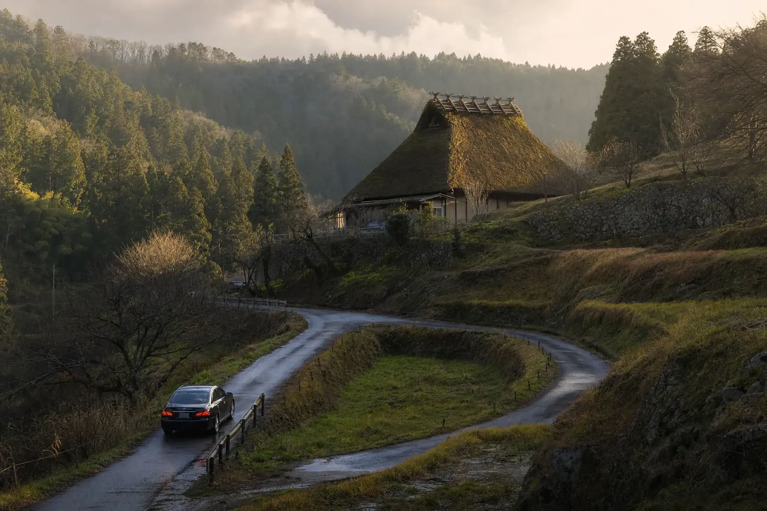 a private car on a winding mountain road approaching the thatched farmhouse at 656 Muroufukano, Uda City, Nara