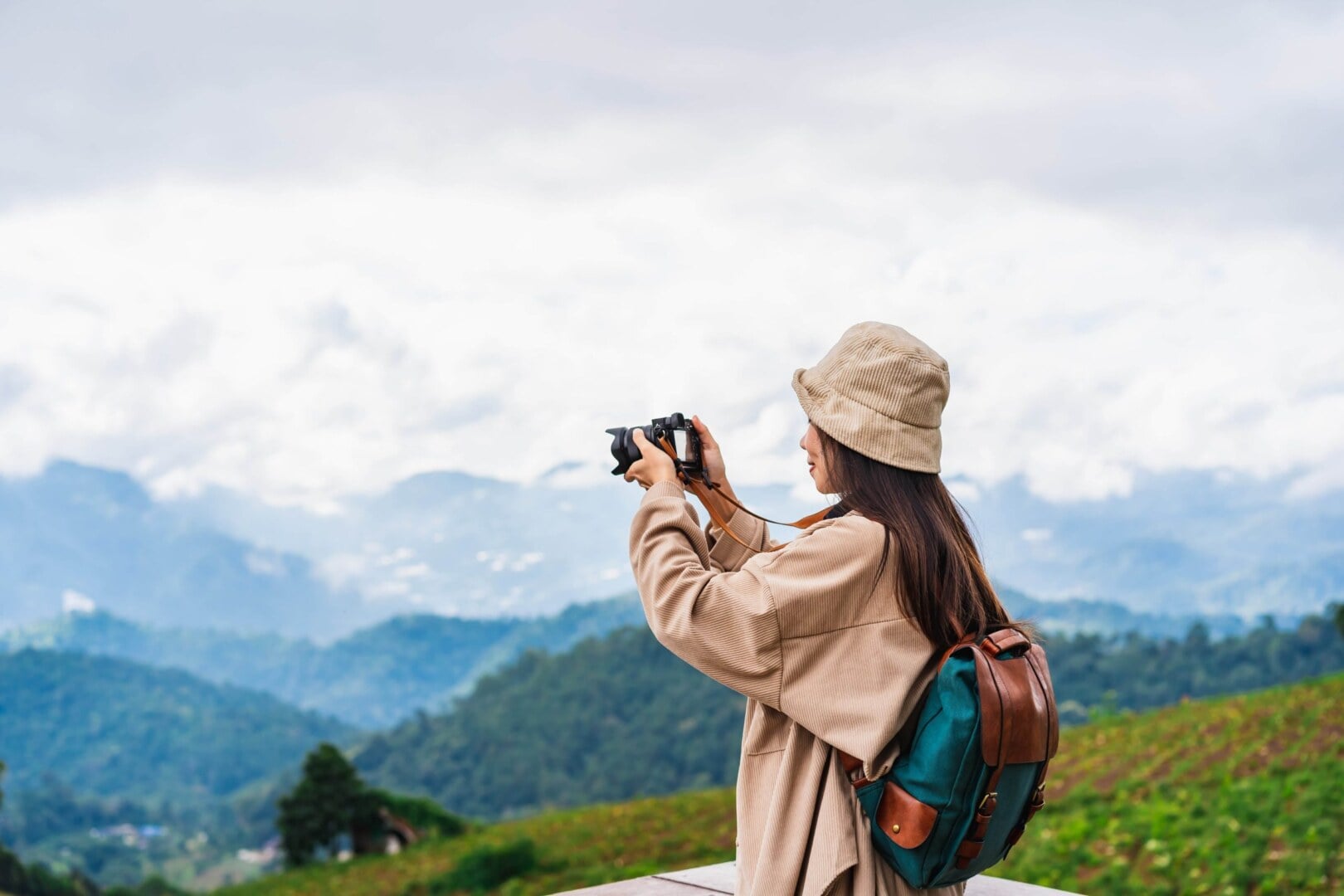 A traveller with a backpack photographing misty mountain ranges from a viewpoint