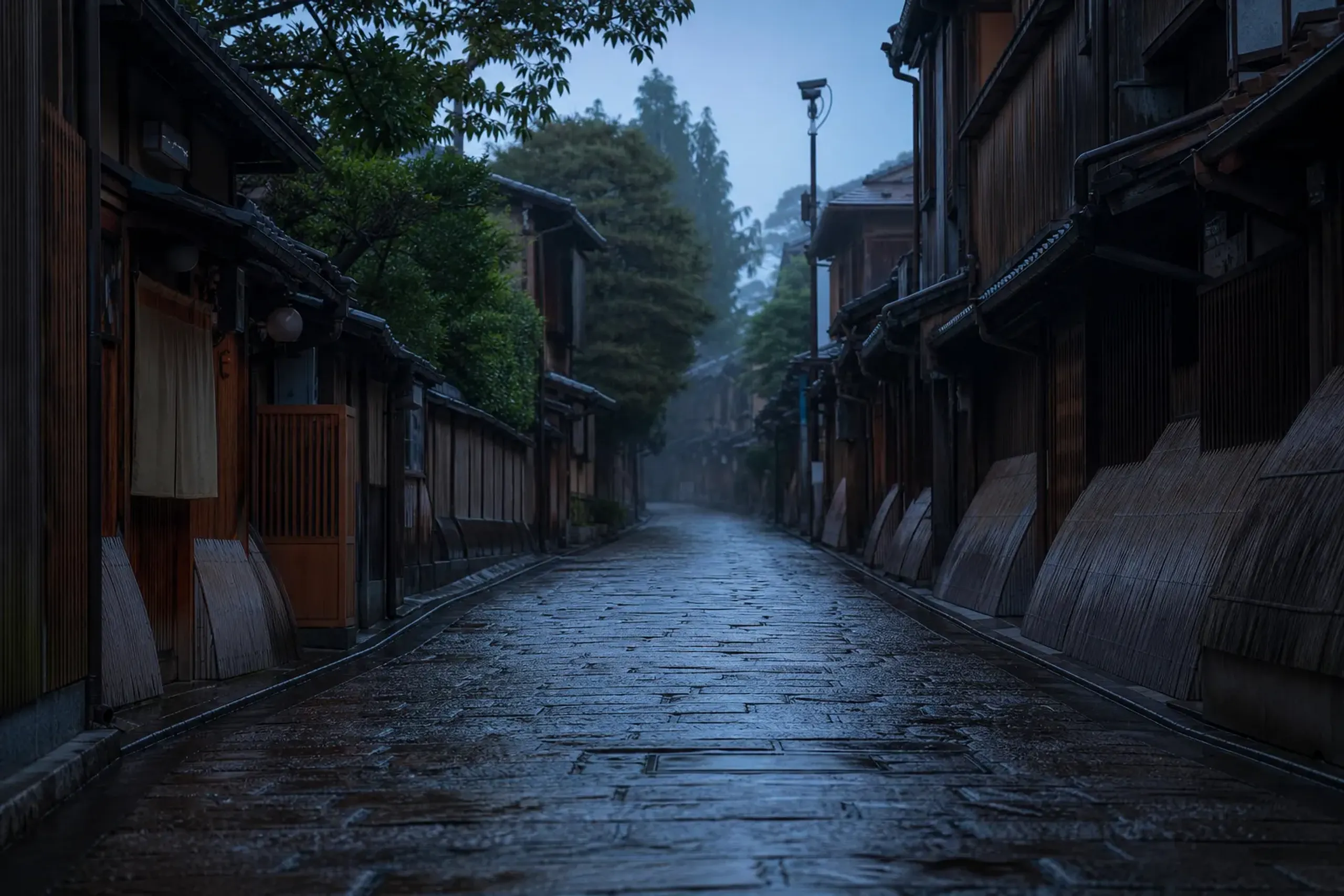 An empty early-morning stone lane in Kyoto's Gion district, wet cobblestones and traditional wooden machiya townhouses lit by soft dawn light, monitored by a small public street camera mounted on a wo