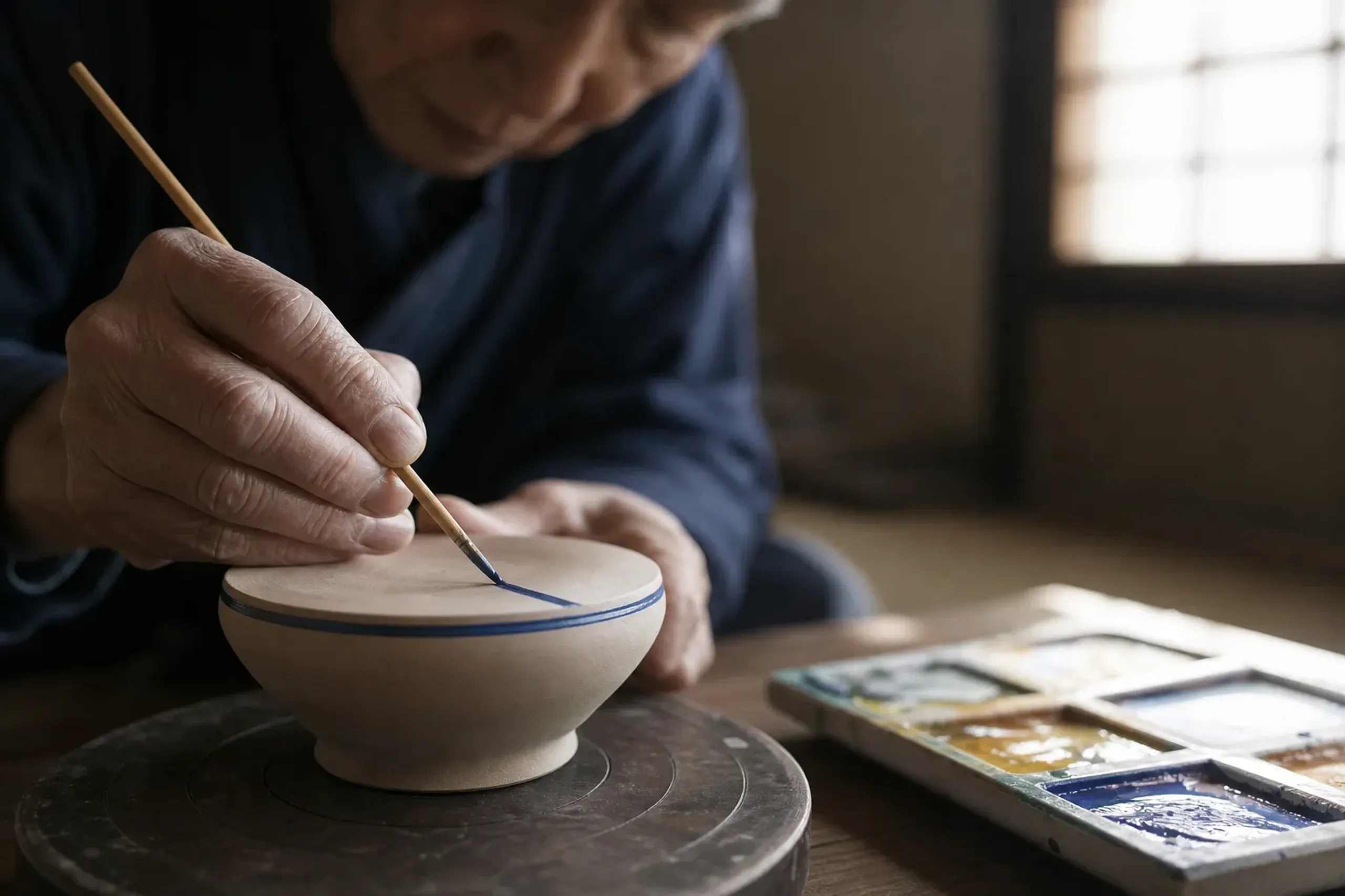 Artist painting Kutani ceramics with a fine brush in a Kanazawa studio