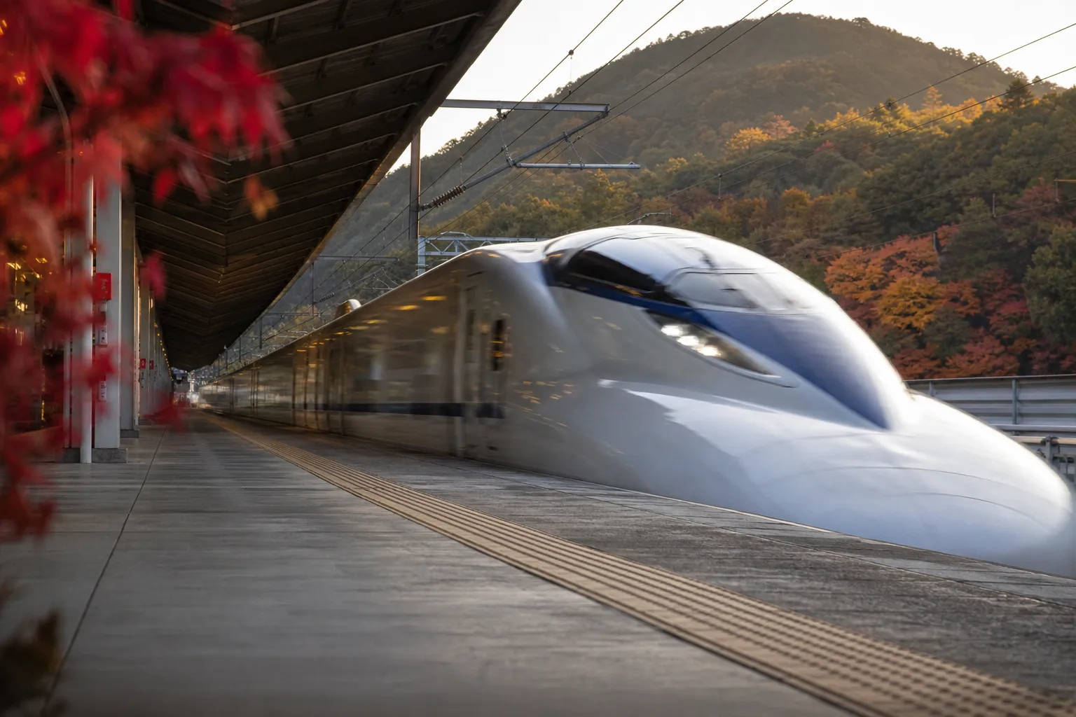 A shinkansen bullet train arriving at a station platform in Japan under soft daylight