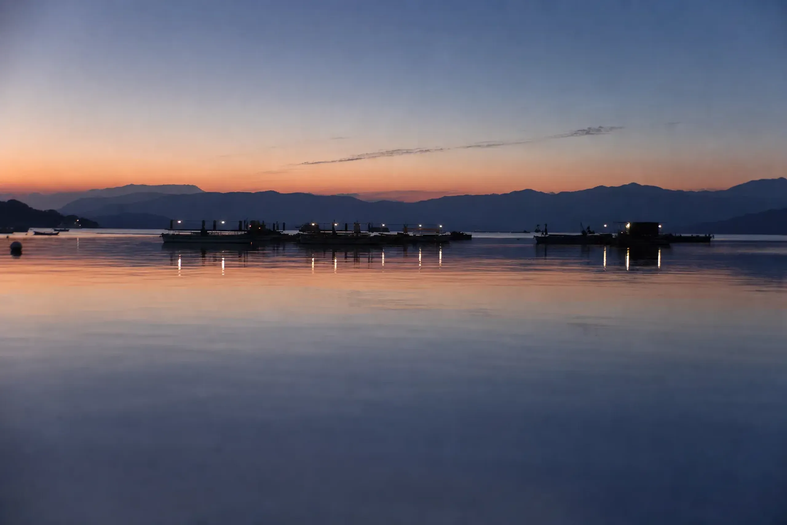 The low, still water-launch platforms clustered near Hatsushima island on Lake Suwa waiting at dusk before the 19:00 start