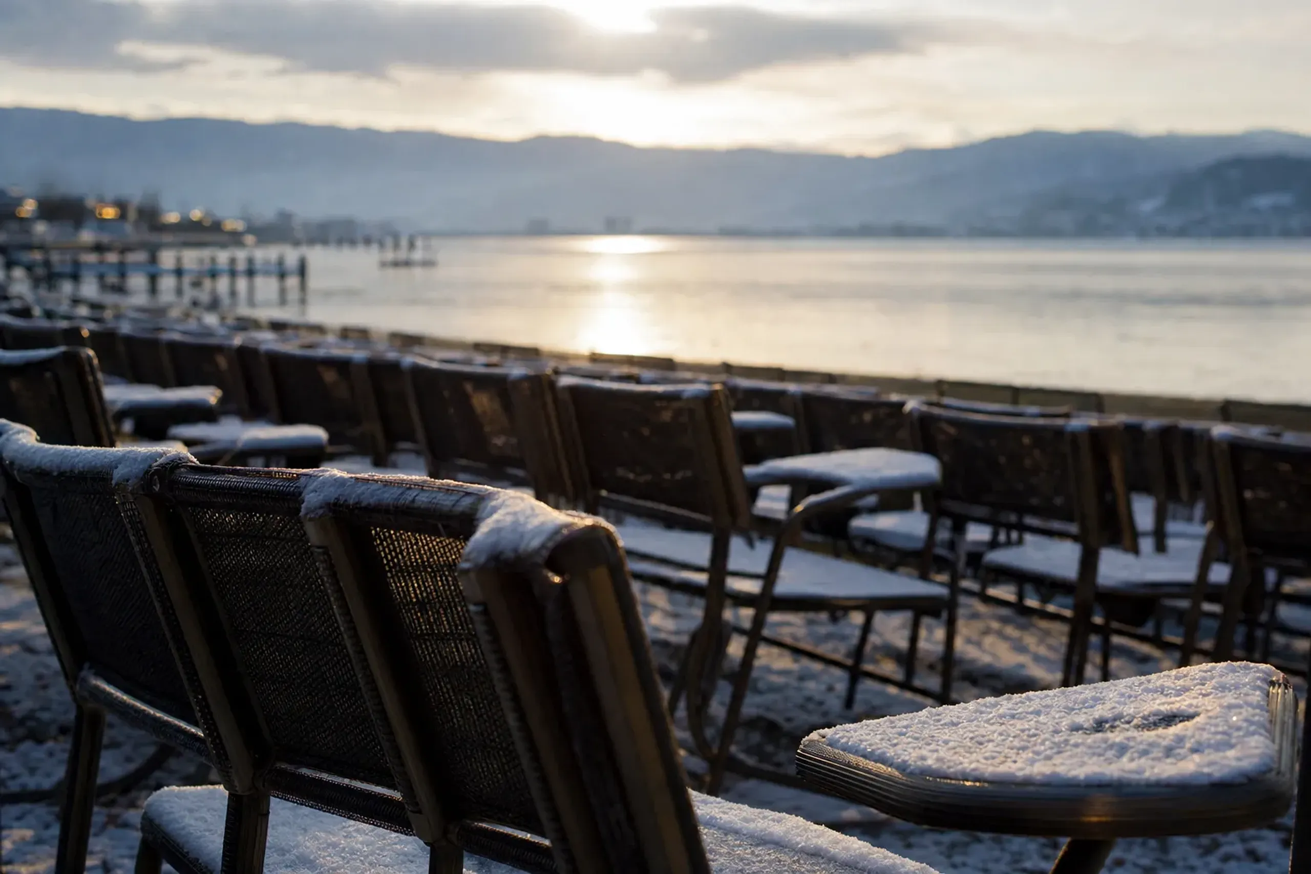 Rows of empty lakeside paired chair seats lining the shore of Kohan Park facing Lake Suwa in the afternoon light