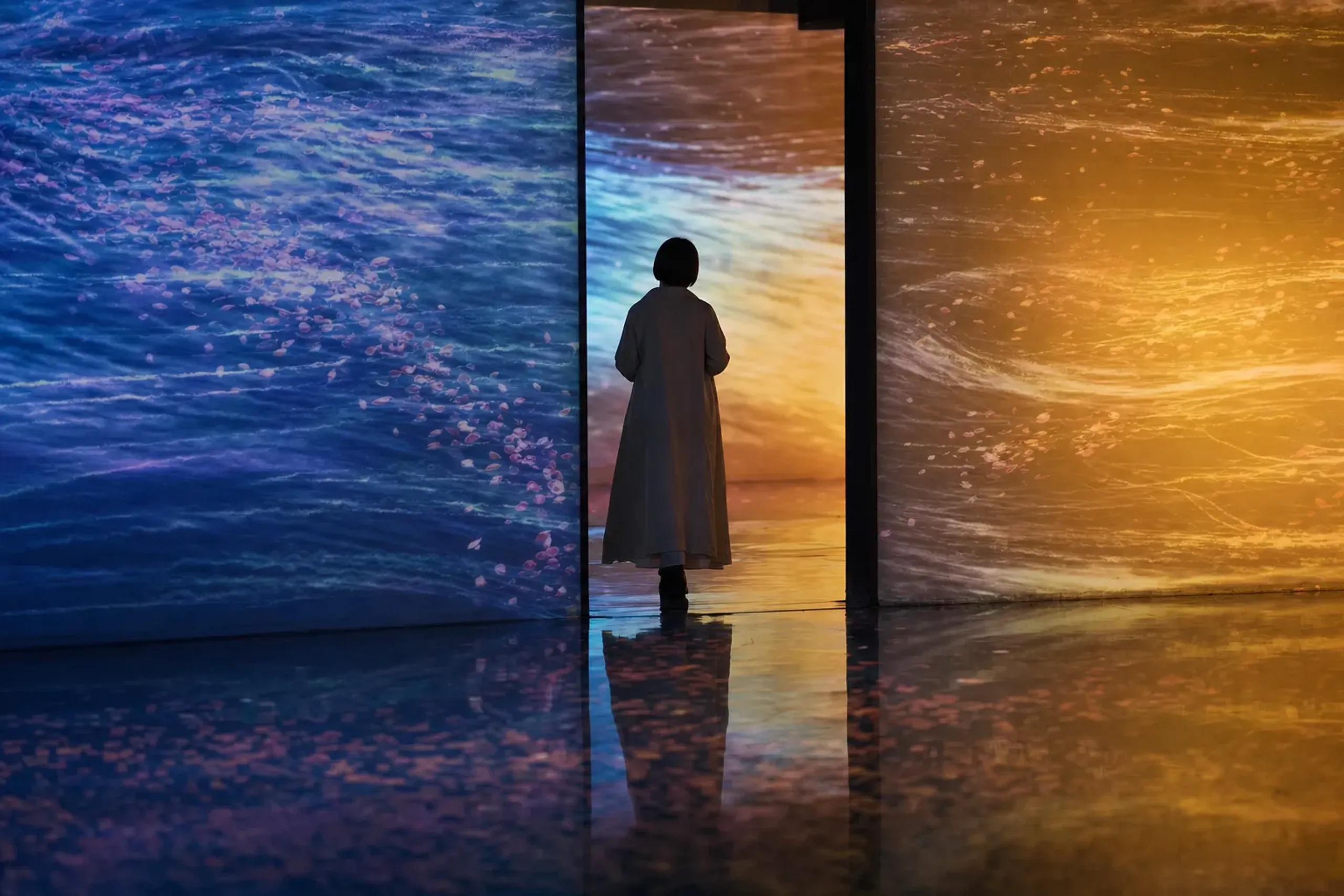 Light installations spilling across walls and floors inside teamLab Borderless, colors bleeding from one room into the next