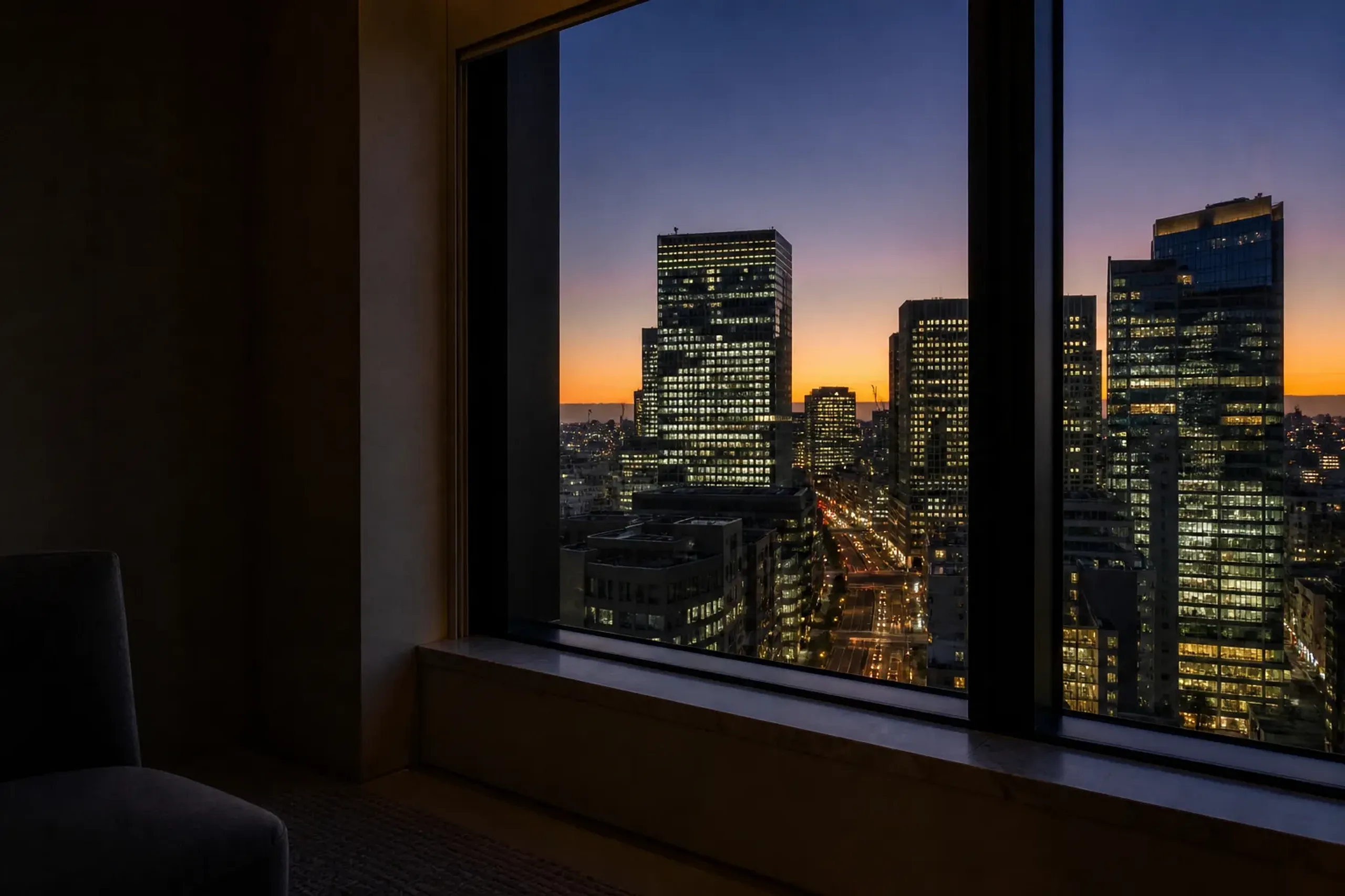 The upper-floor guest room windows of Four Seasons Hotel Tokyo at Otemachi overlooking the Otemachi financial district skyline at dusk