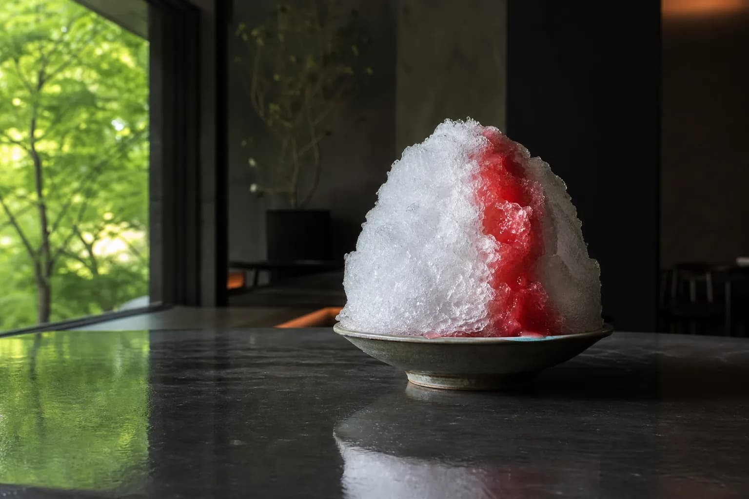 the Tottori watermelon kakigori of Hotel New Otani Tokyo, a mound of snow-fine Nikko natural ice crowned with vivid red watermelon syrup, served on a polished table in the air-conditioned calm of KATO