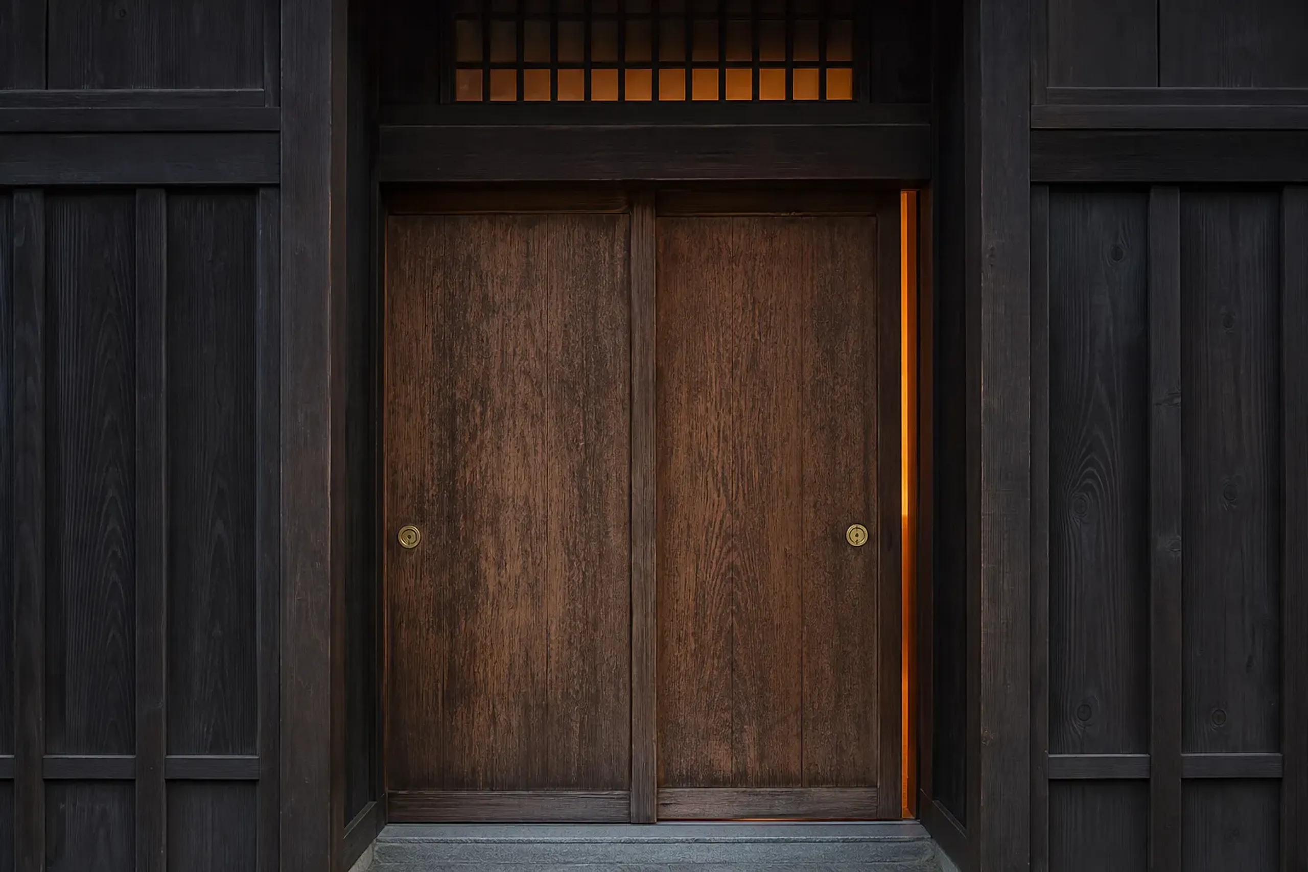 An unlabeled wooden sliding door in a Kyoto machiya at twilight, an introduction-only venue